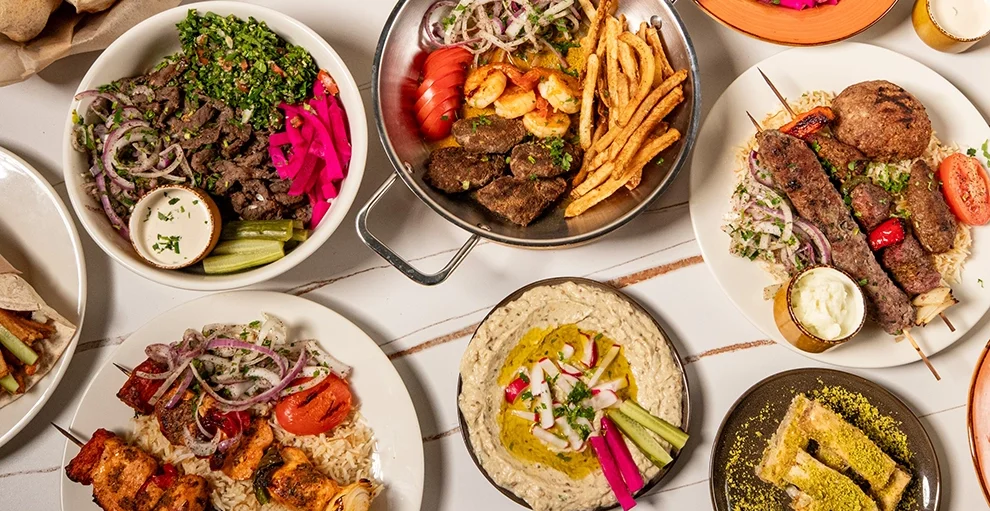 Overhead spread of Lebanese mezze, falafel, kebabs, hummus, and pita