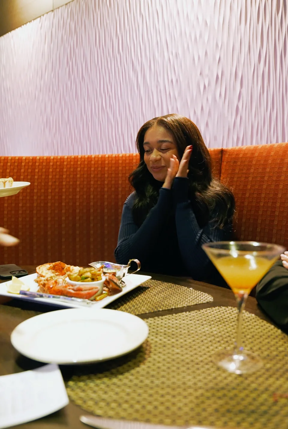 A woman joyfully clapping at a seafood dish in a restaurant setting.