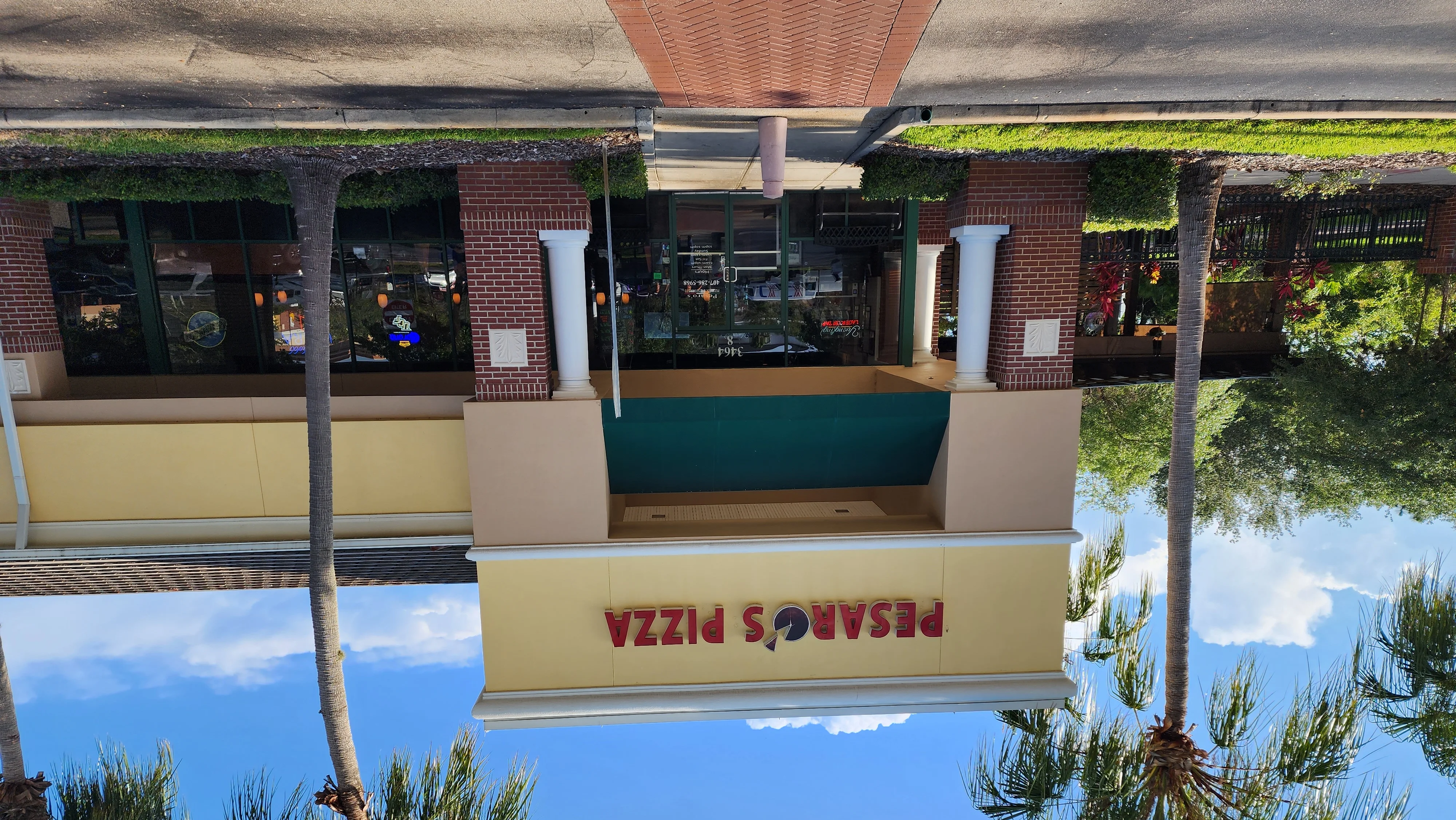 Exterior view of Pesaro's Pizza restaurant with palm trees