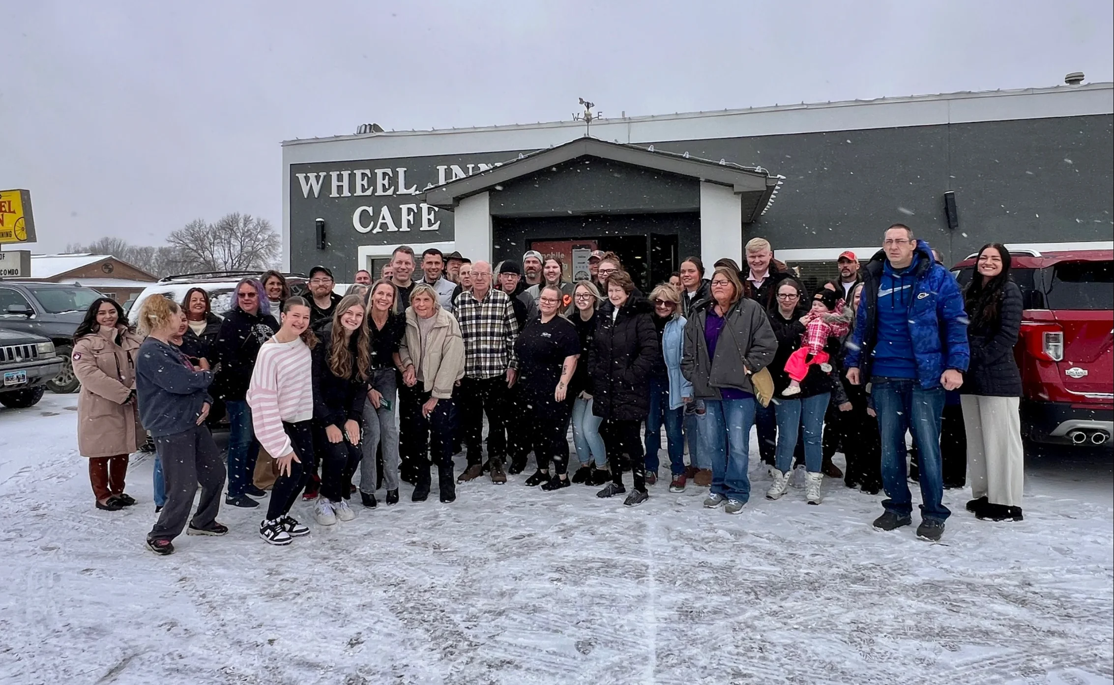 Group photo outside Wheel Inn Cafe in snowy weather