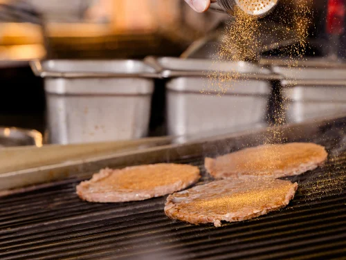 Chef seasoning grilled steak on a hot griddle