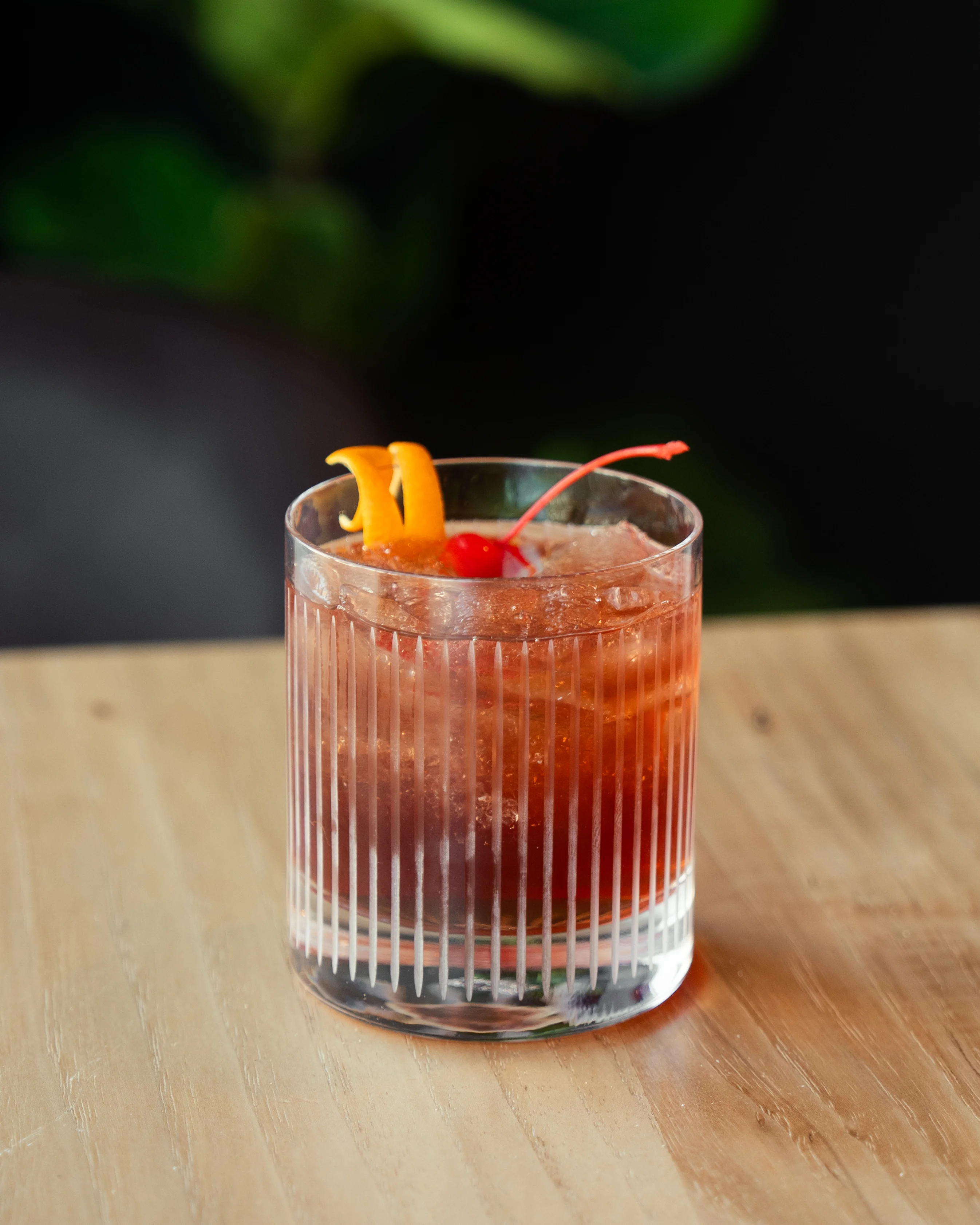 Classic cocktail garnished with cherry and orange peel
