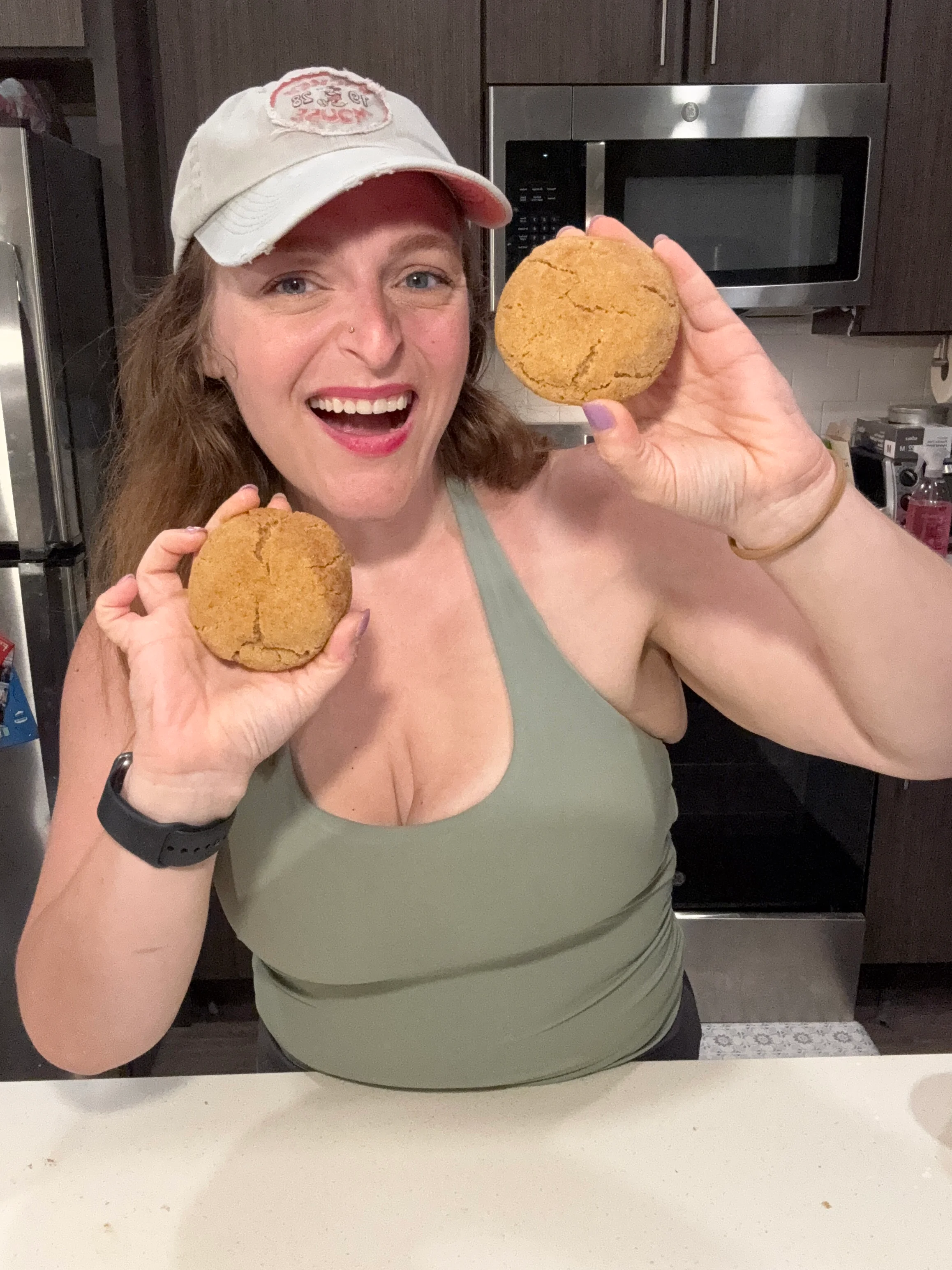 Person joyfully holding freshly baked ginger cookies in a modern kitchen