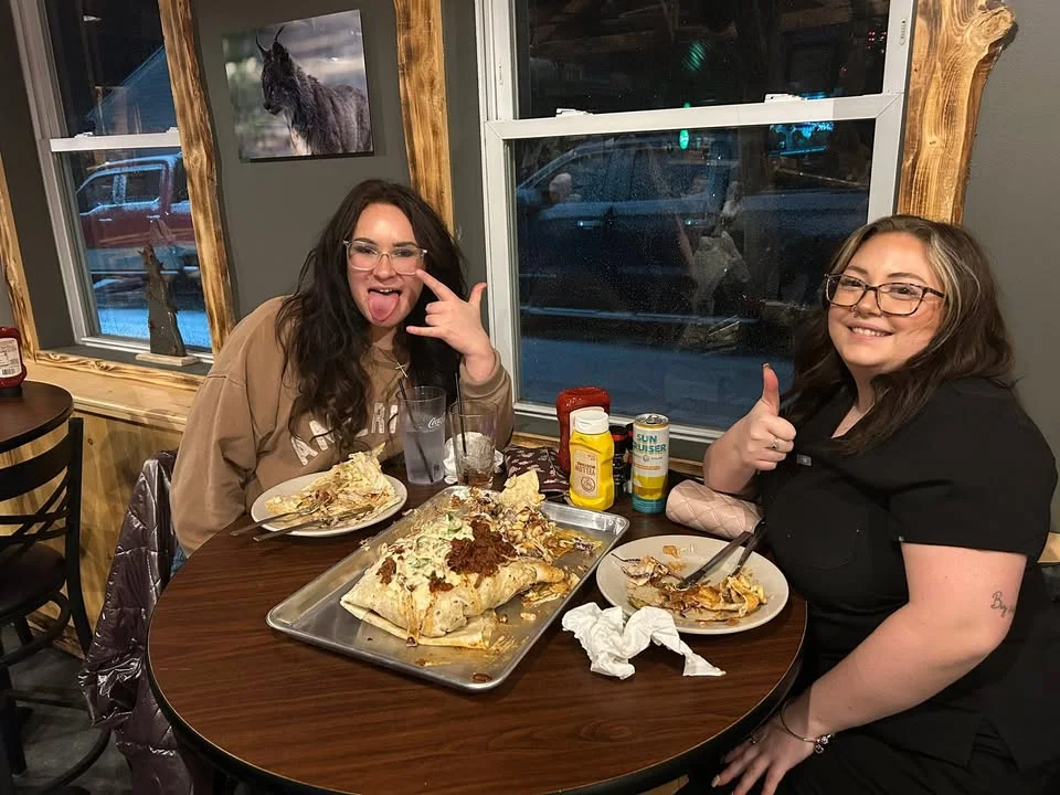 Two friends enjoying a giant burrito in a cozy restaurant