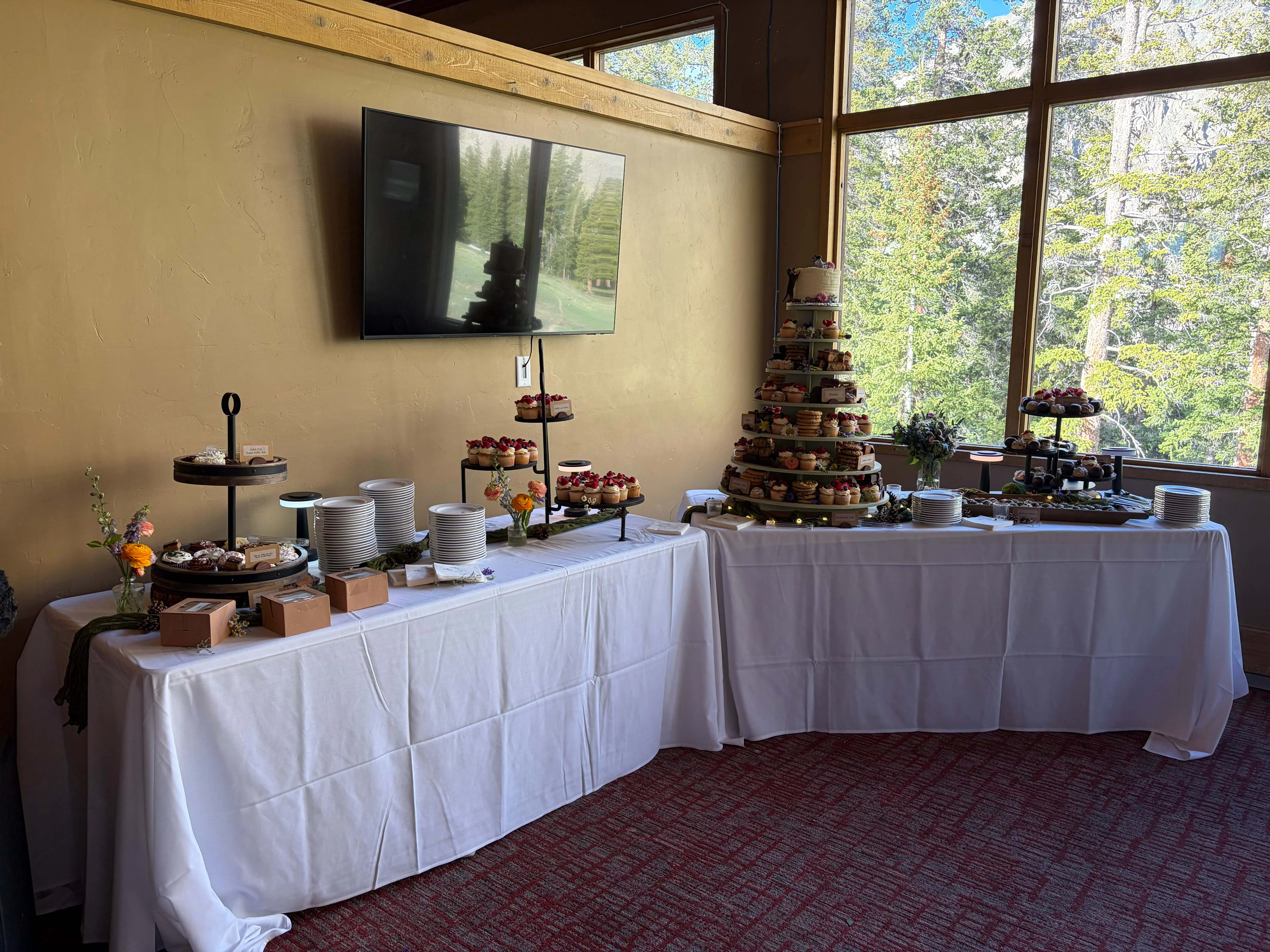 Dessert buffet with decorated cupcakes, pastries, flowers, and stacked plates