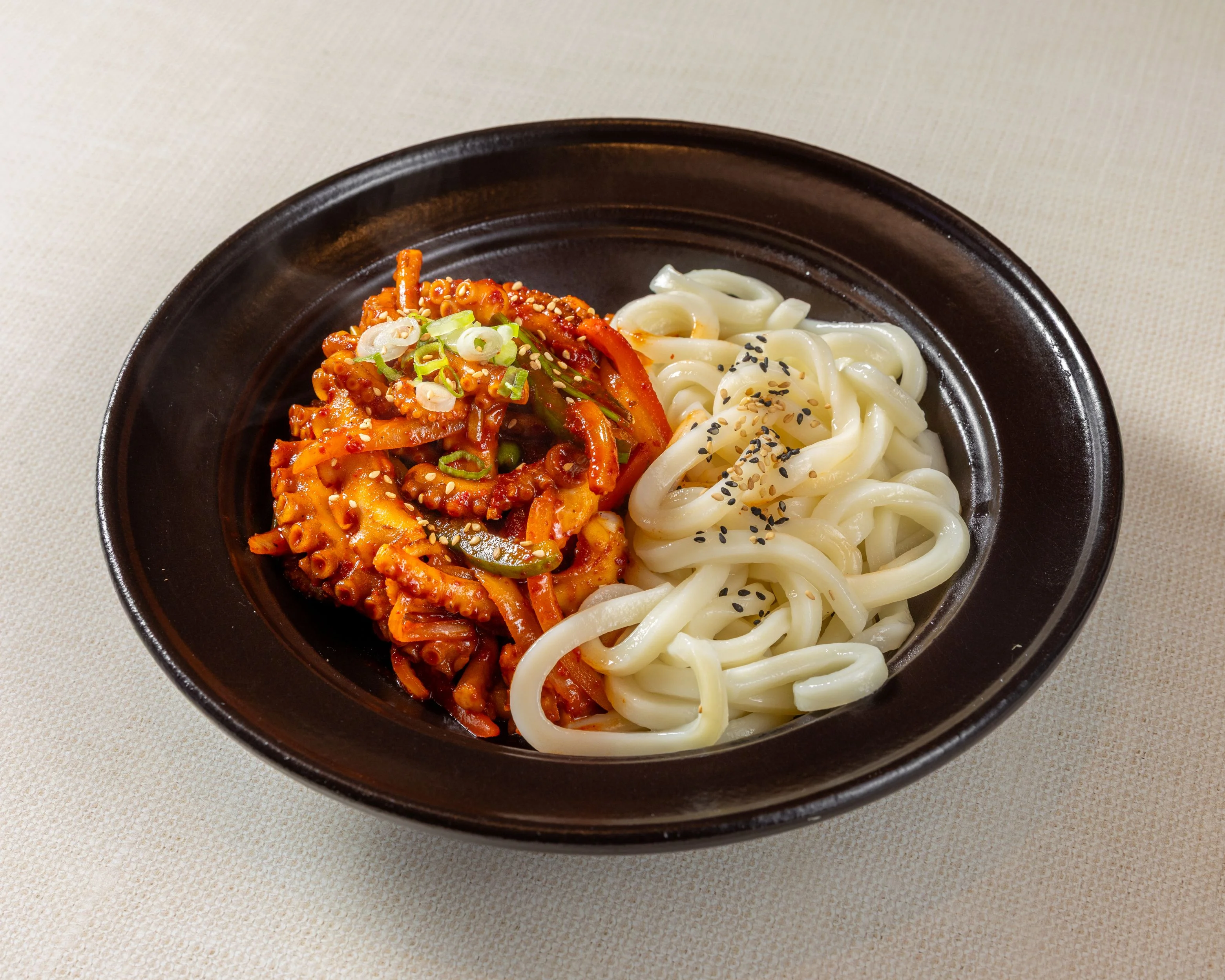Korean nakji bokkeum with chewy noodles on a black plate