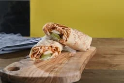 Delicious chicken wrap with pickles on a wooden board