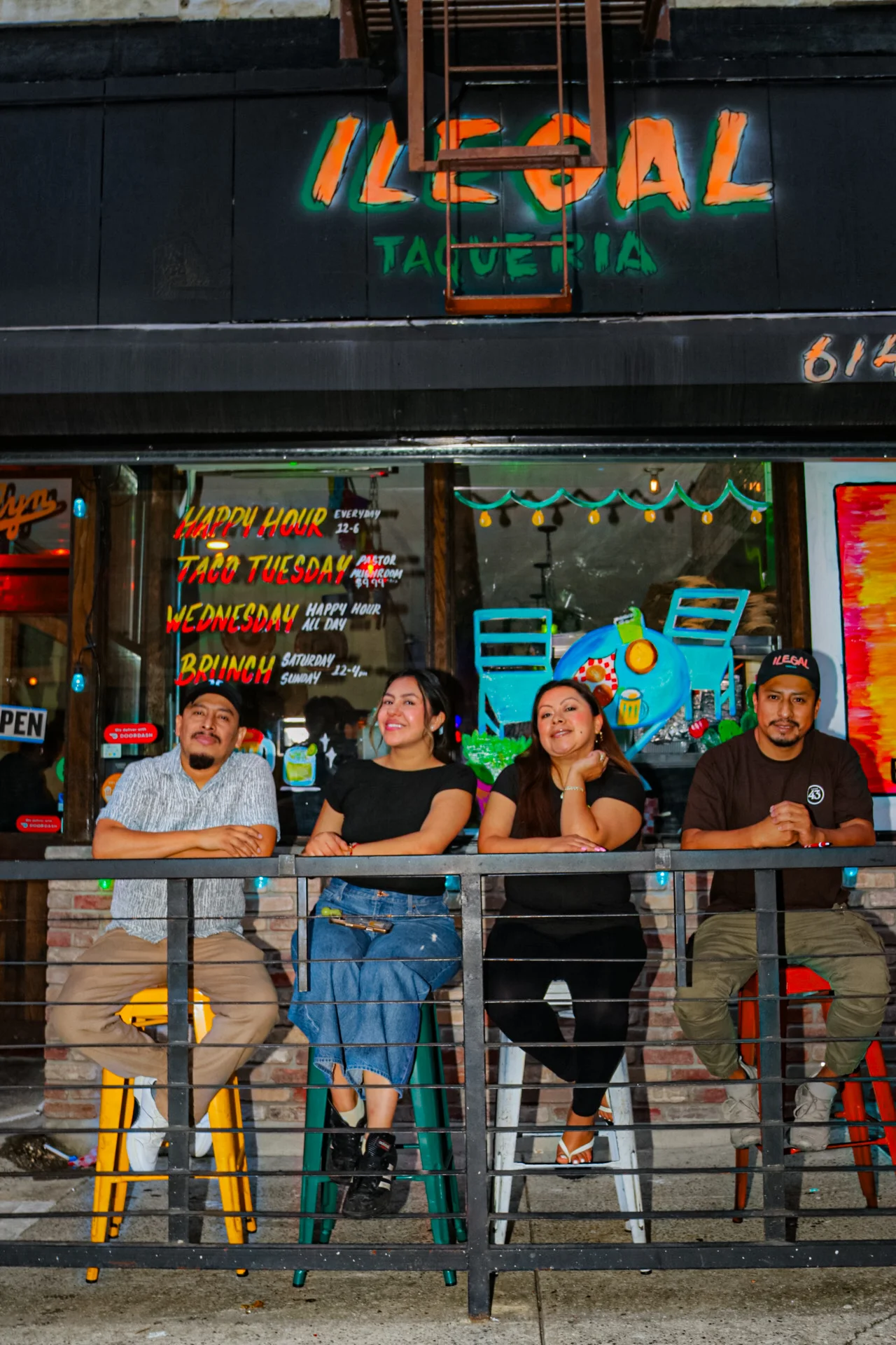 Staff posing outside Illegal Taqueria with vibrant decor