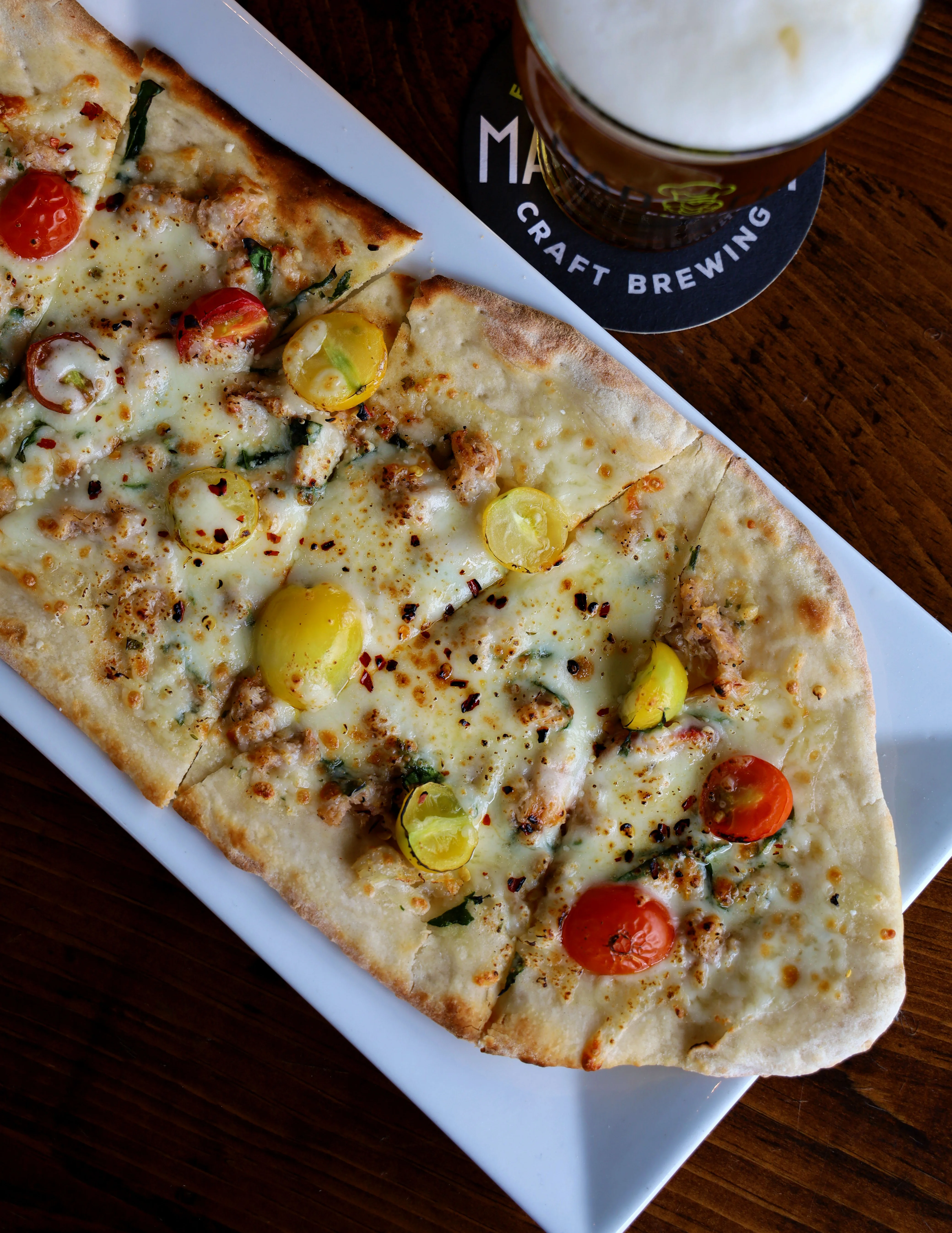 Delicious chicken broccoli Alfredo flatbread topped with cheese and herbs.