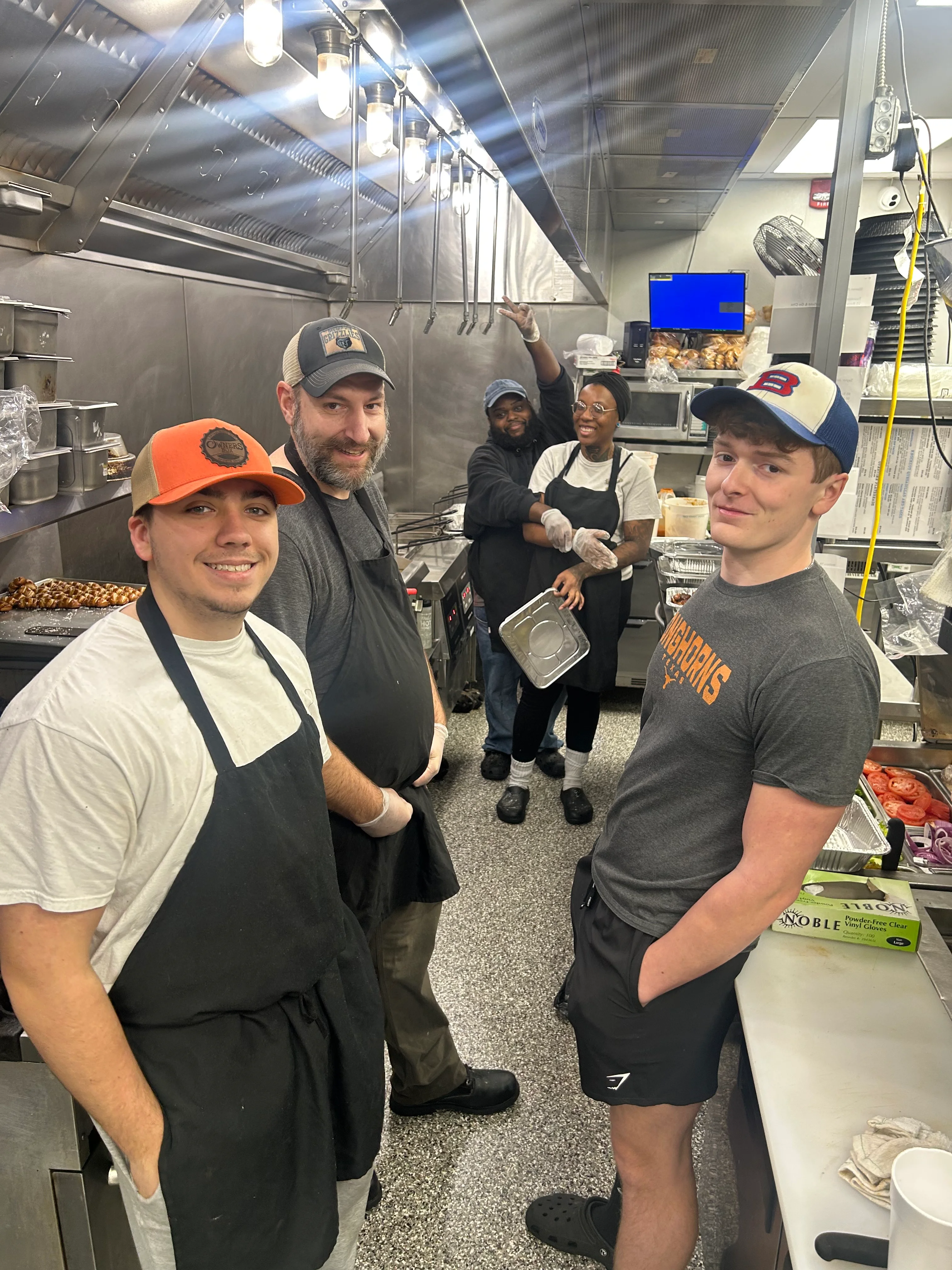 Chefs smiling in a busy restaurant kitchen