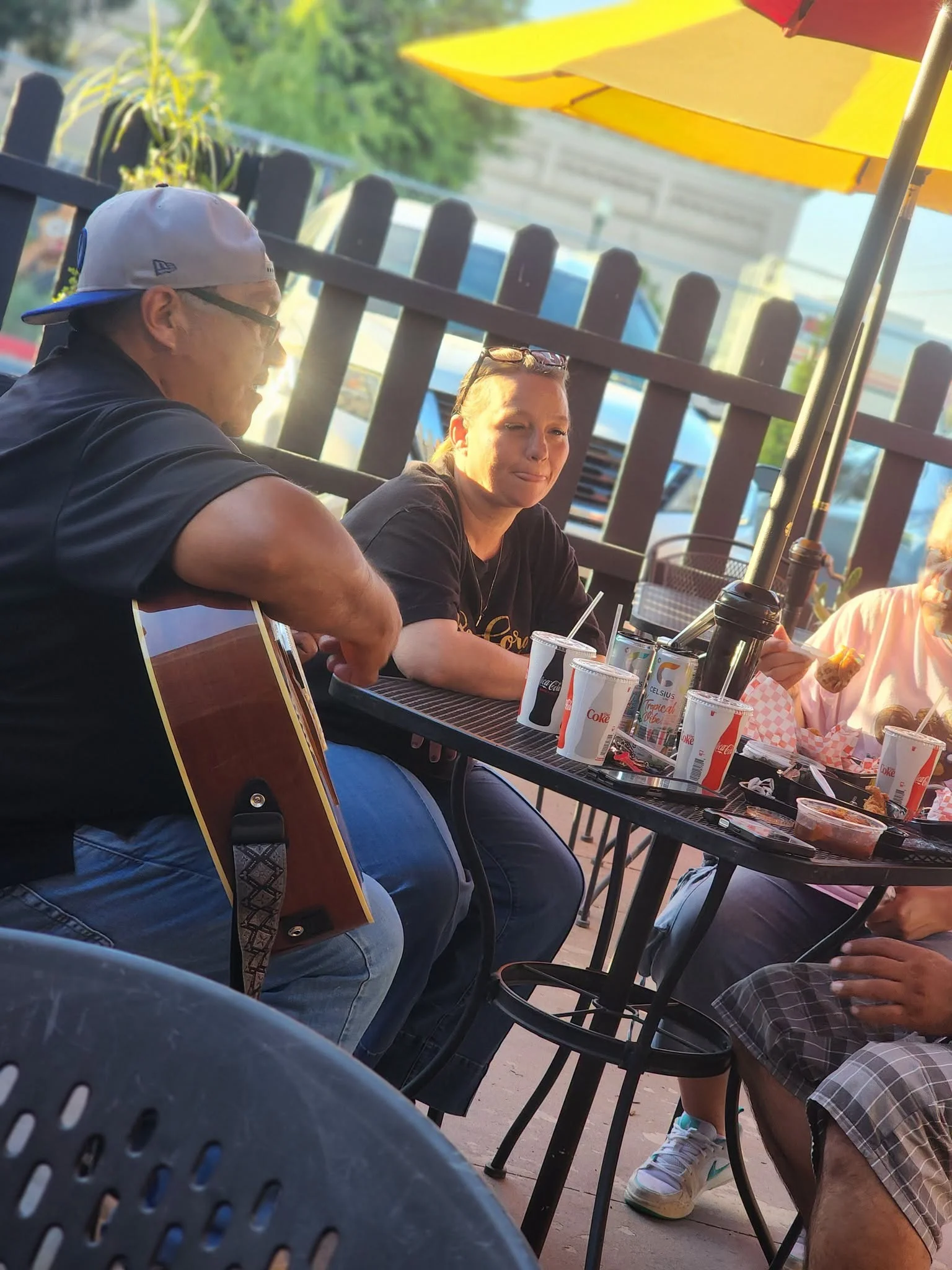 Group enjoying music and food at an outdoor dining table