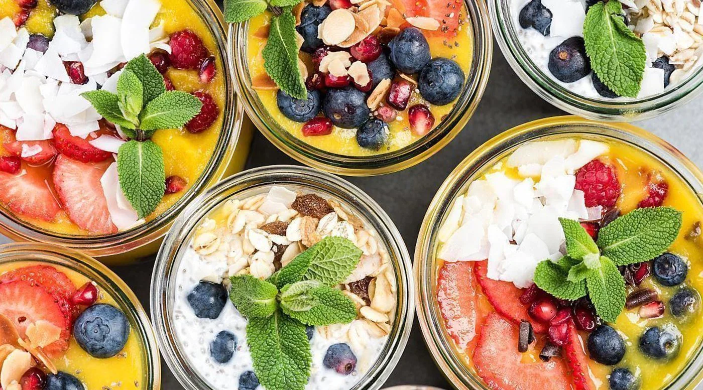 Colorful fruit parfaits in jars with yogurt and granola