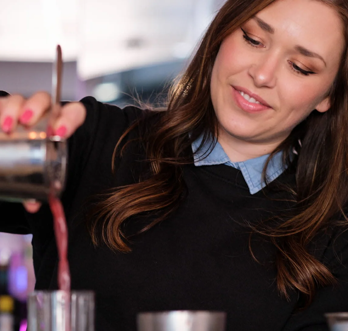 Bartender pouring a cocktail at a stylish bar counter