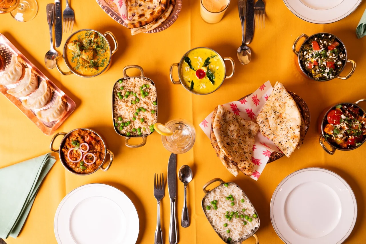 Assorted Indian dishes including curry, naan, and rice on a vibrant table setting