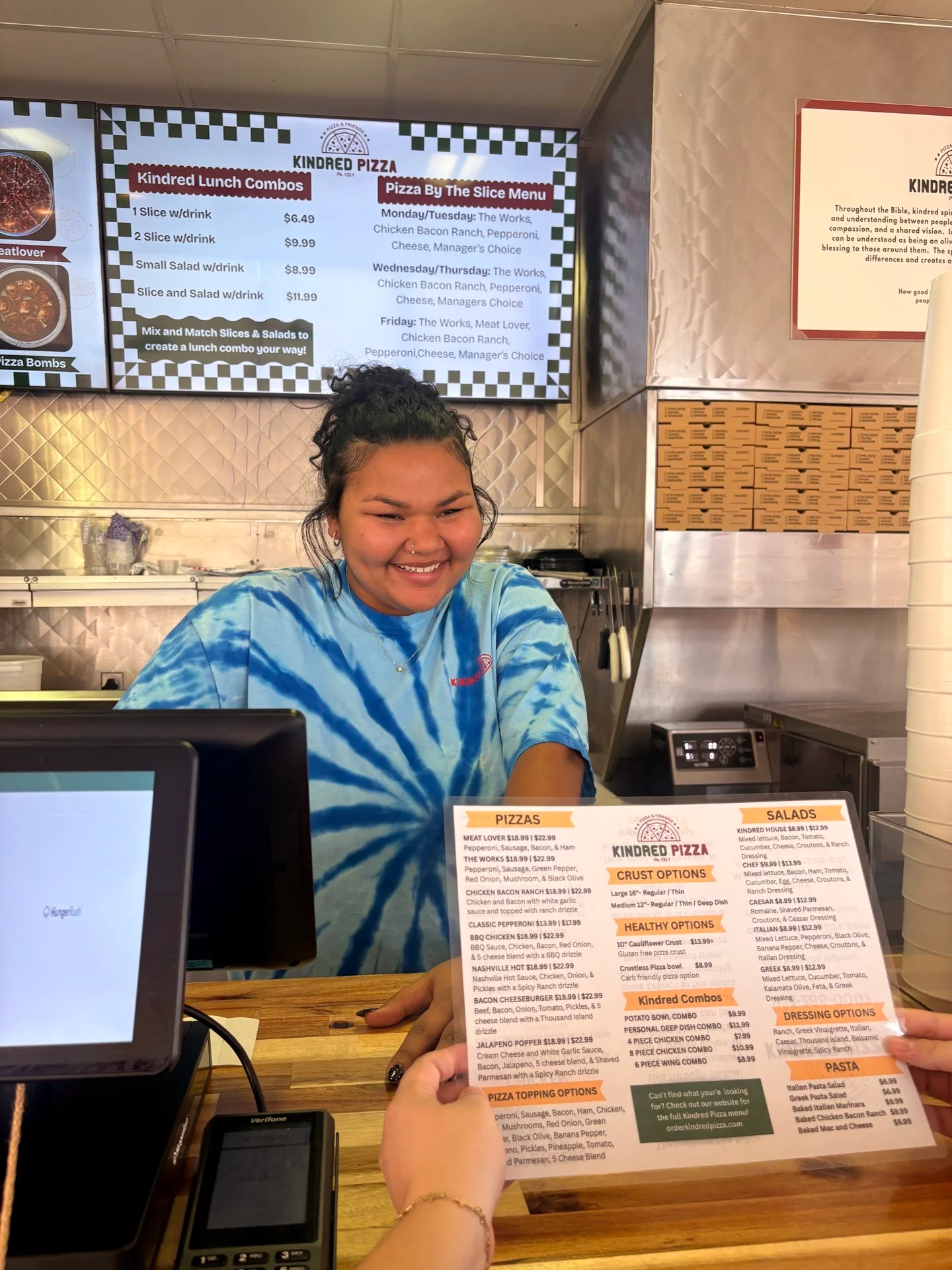 Friendly staff at Kindred Pizza with menu options displayed