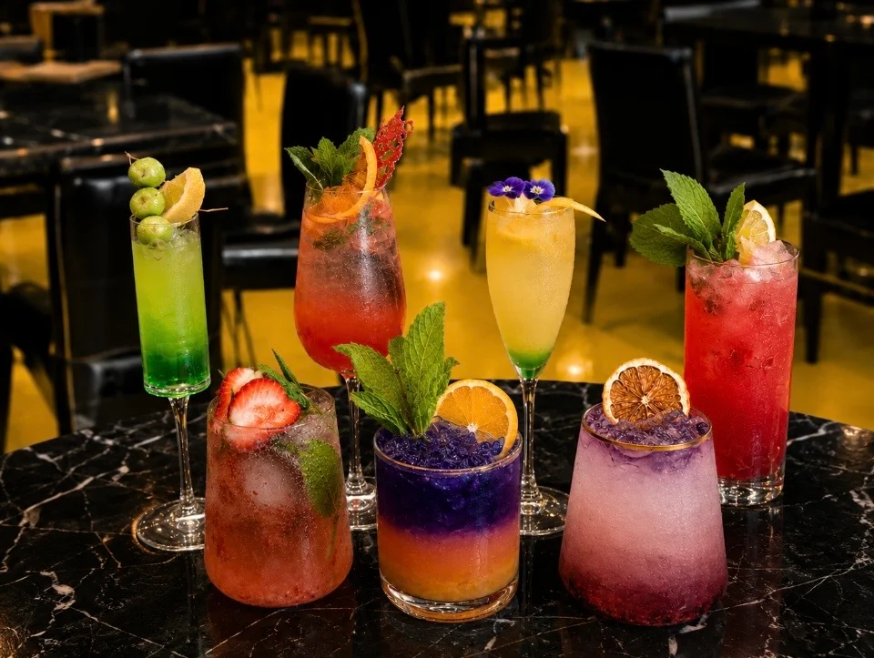 Colorful cocktails arranged on a marble table in a restaurant setting.