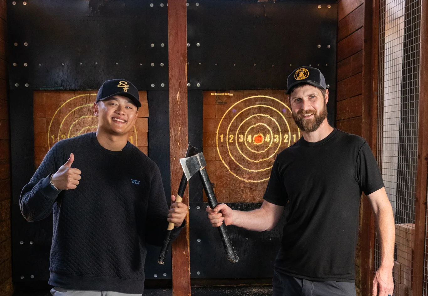 Two friends enjoying axe throwing at an outdoor venue
