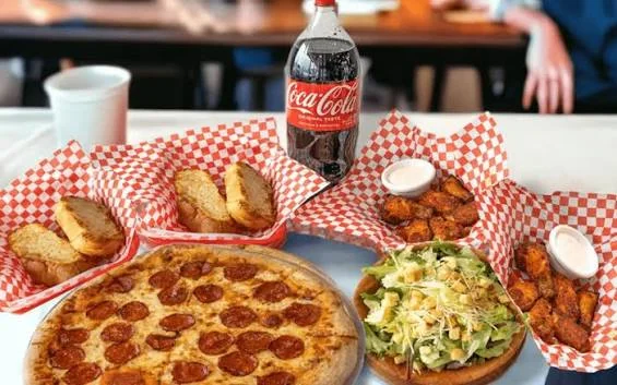 Pepperoni pizza with sides and a soda in a casual dining setting