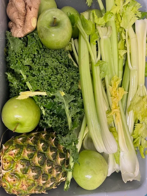 Fresh produce for a green juice, featuring kale, celery, and pineapple.