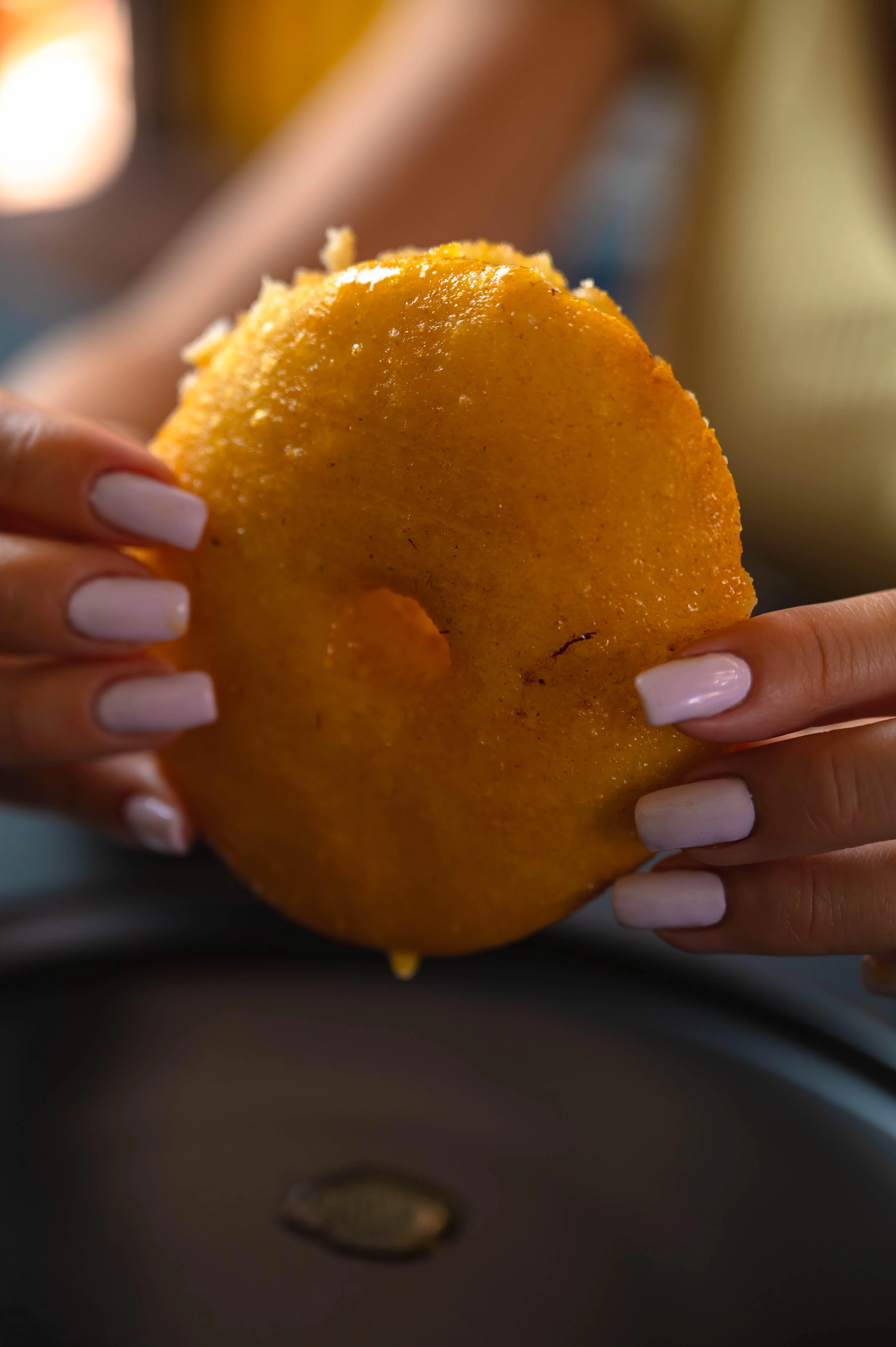 Golden arepa held by hands, a staple of Colombian cuisine