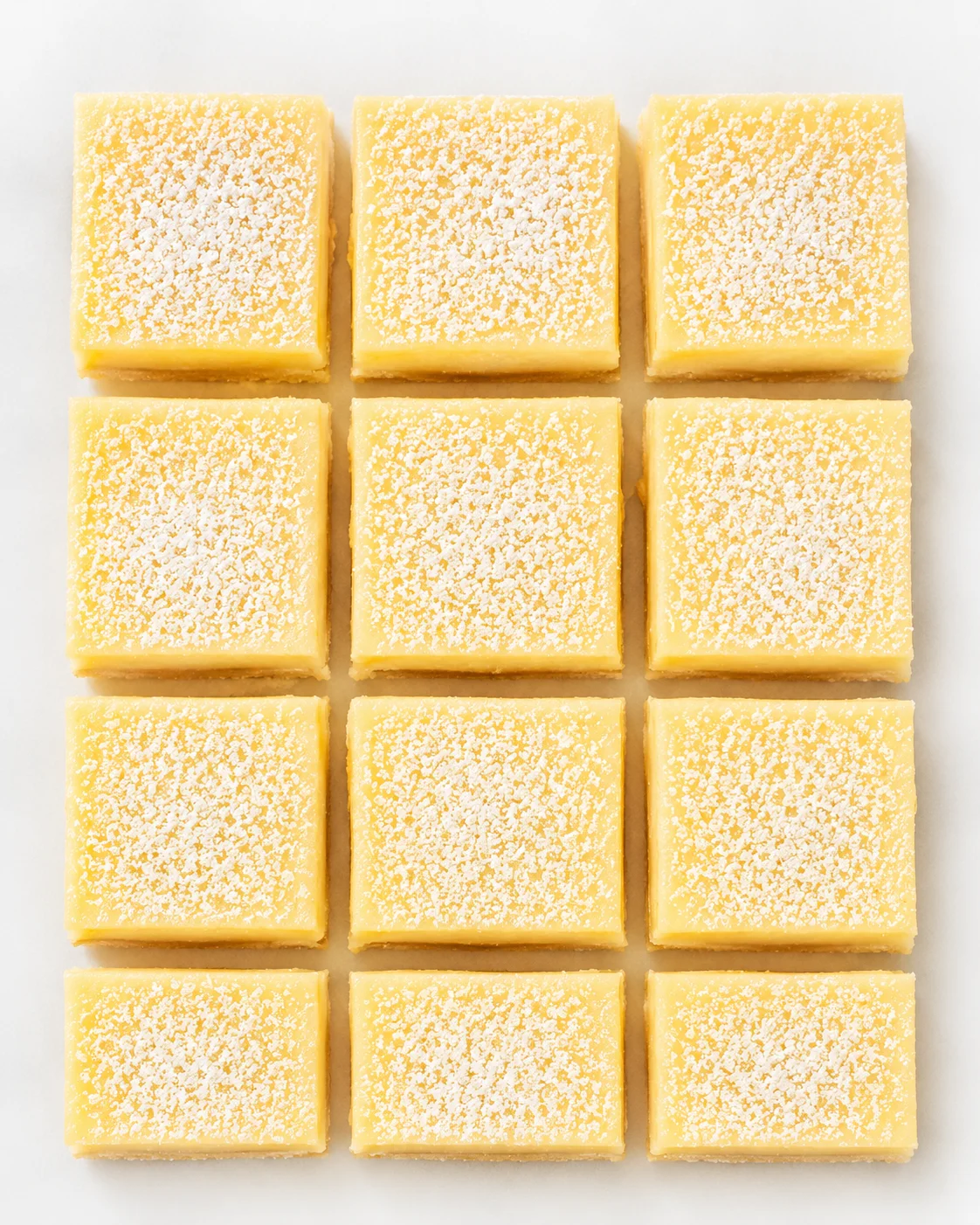 Lemon bars dusted with powdered sugar on a white background