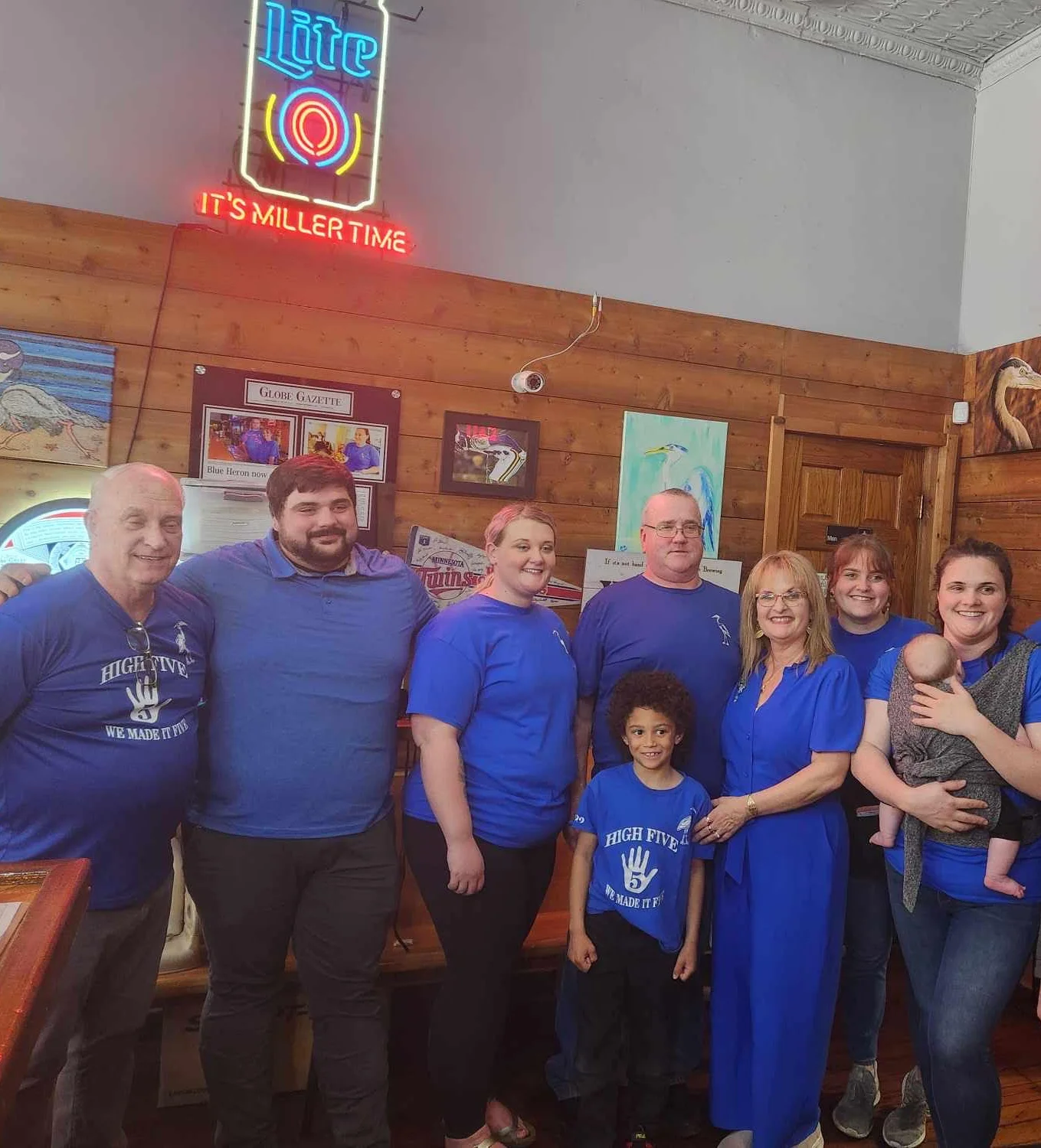 Group of people in blue shirts posing inside a restaurant.