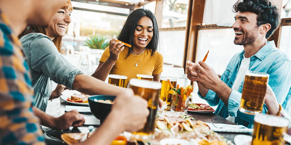 Group of friends enjoying food and drinks at a lively restaurant