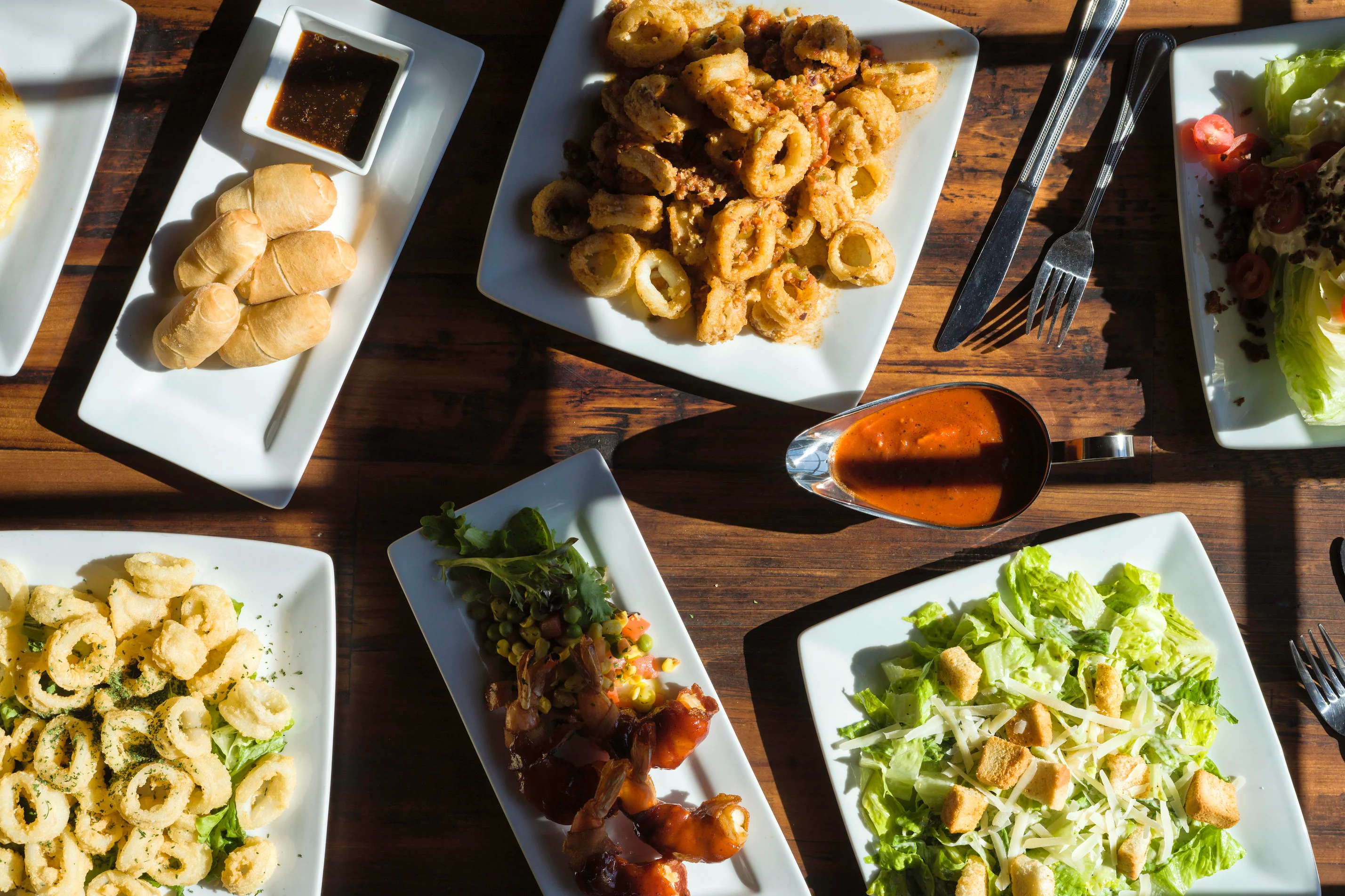 Assorted appetizers including calamari and shrimp in a vibrant restaurant setting