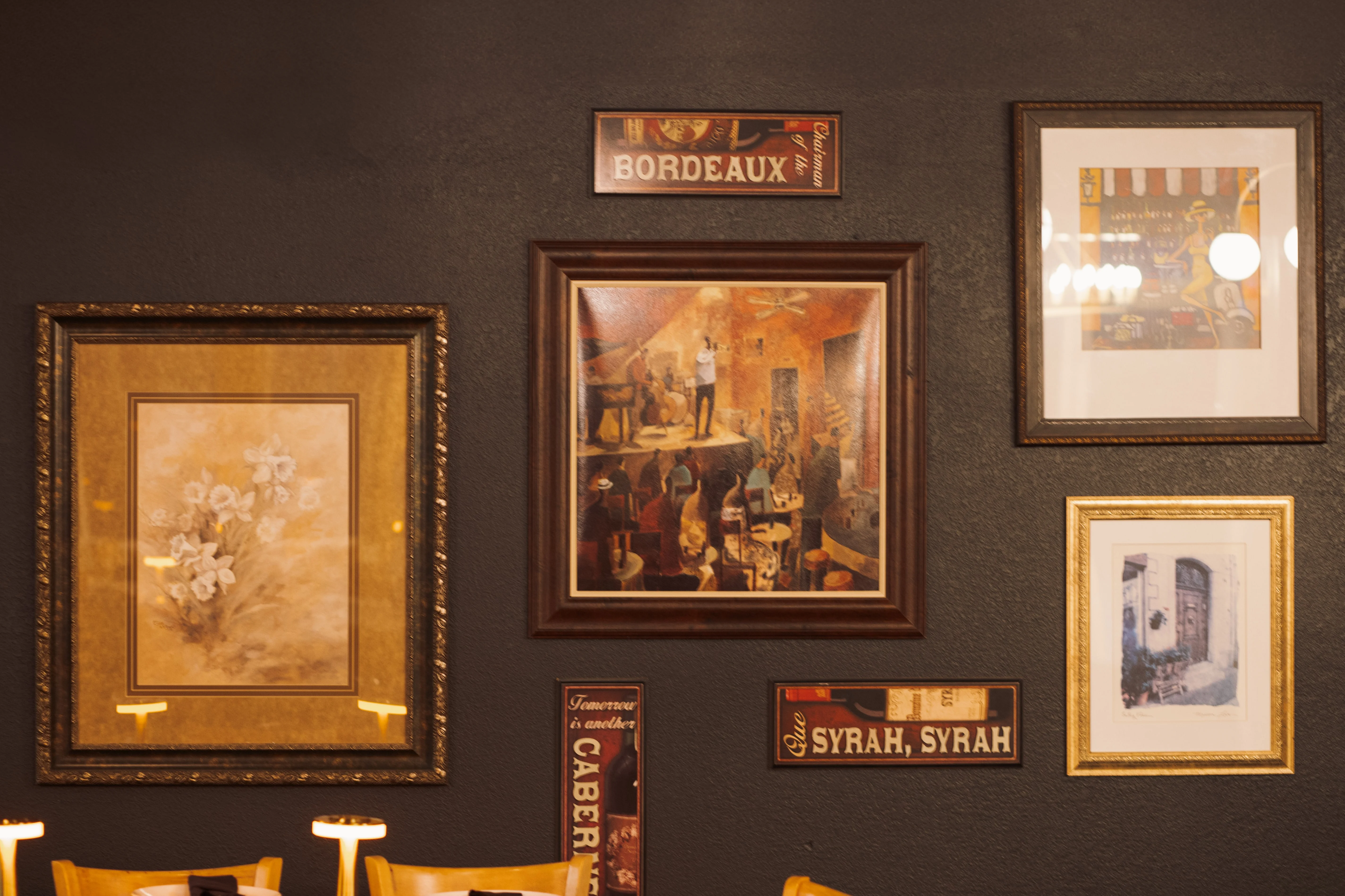 Artistic restaurant wall decor with framed paintings and wine signs