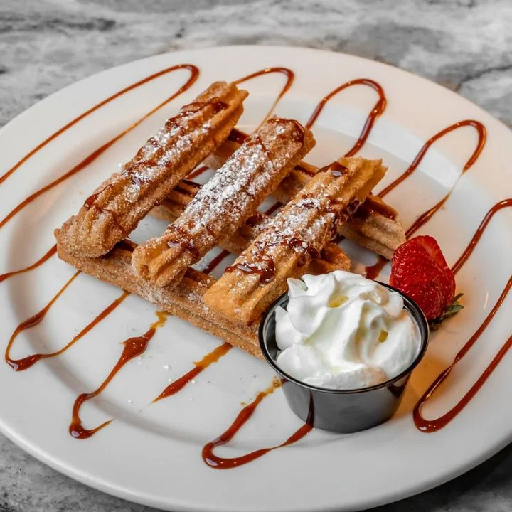 Delicious churros drizzled with caramel sauce and whipped cream