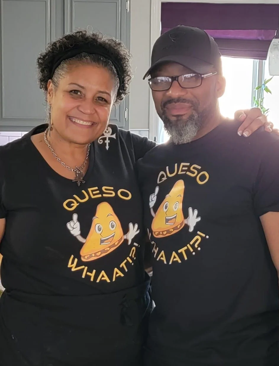Chefs smiling in matching Queso shirts in a cozy kitchen