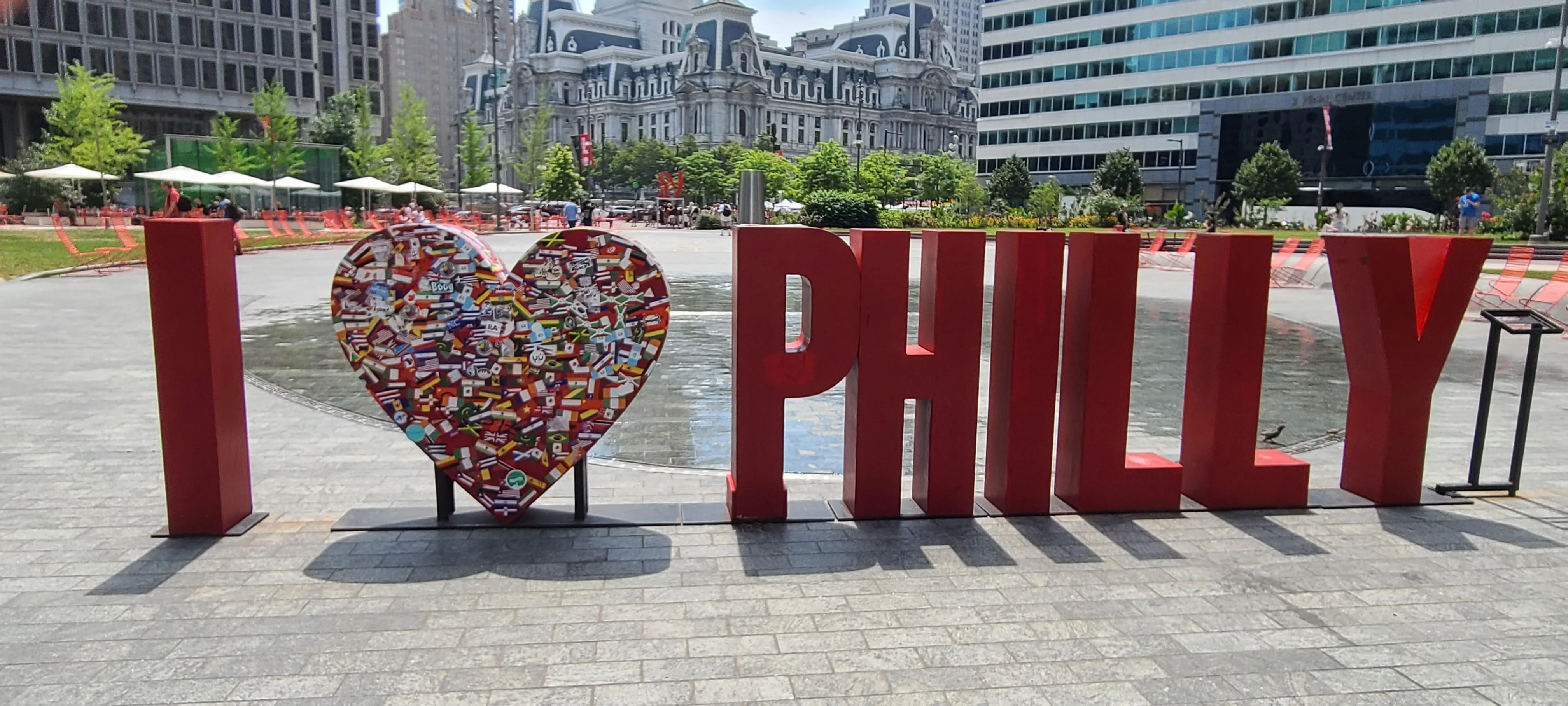 Colorful 'I Love Philly' sign with flags in a city park