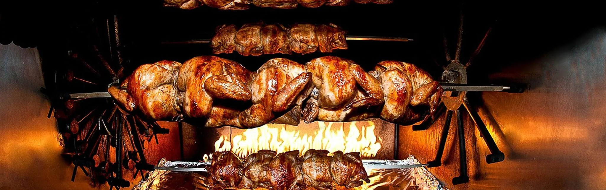 Rotisserie chicken cooking over an open flame