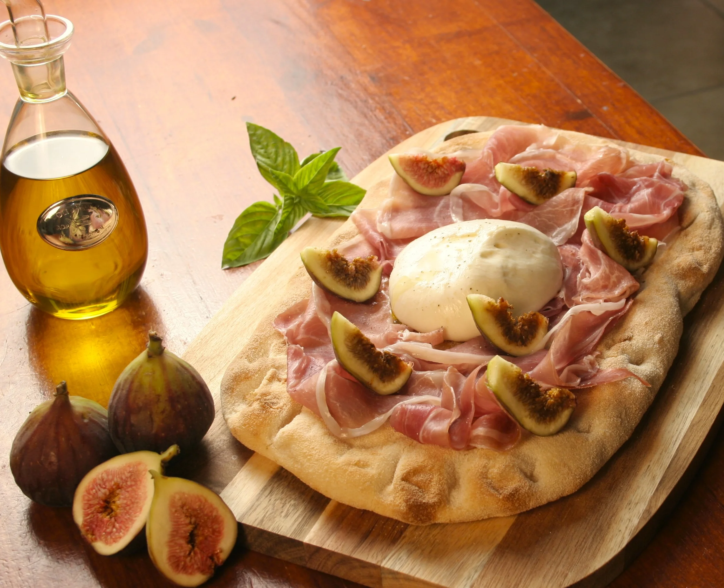 Fichi Roman pinsa topped with fresh figs, prosciutto and burrata on a wooden board at Daje Pinsa Roman Pizza in Orlando.