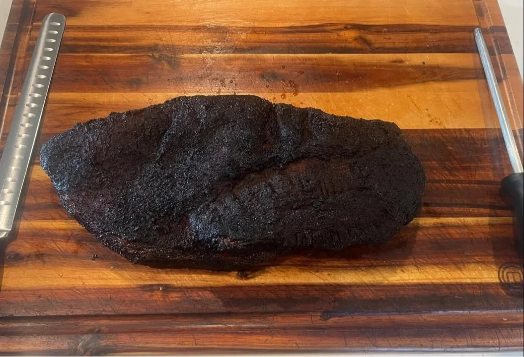Smoked brisket resting on a wooden cutting board