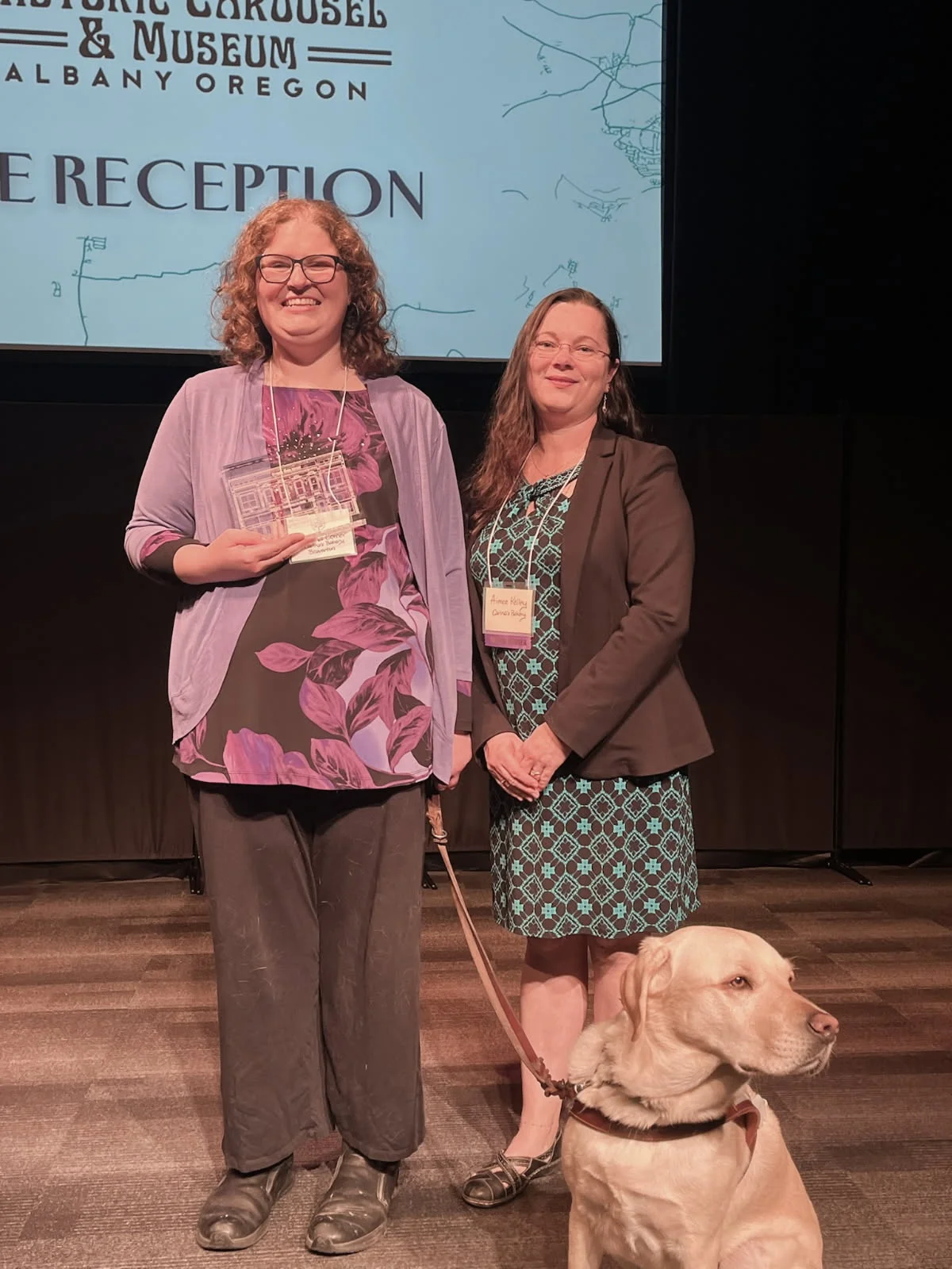 Award ceremony with two women and a service dog