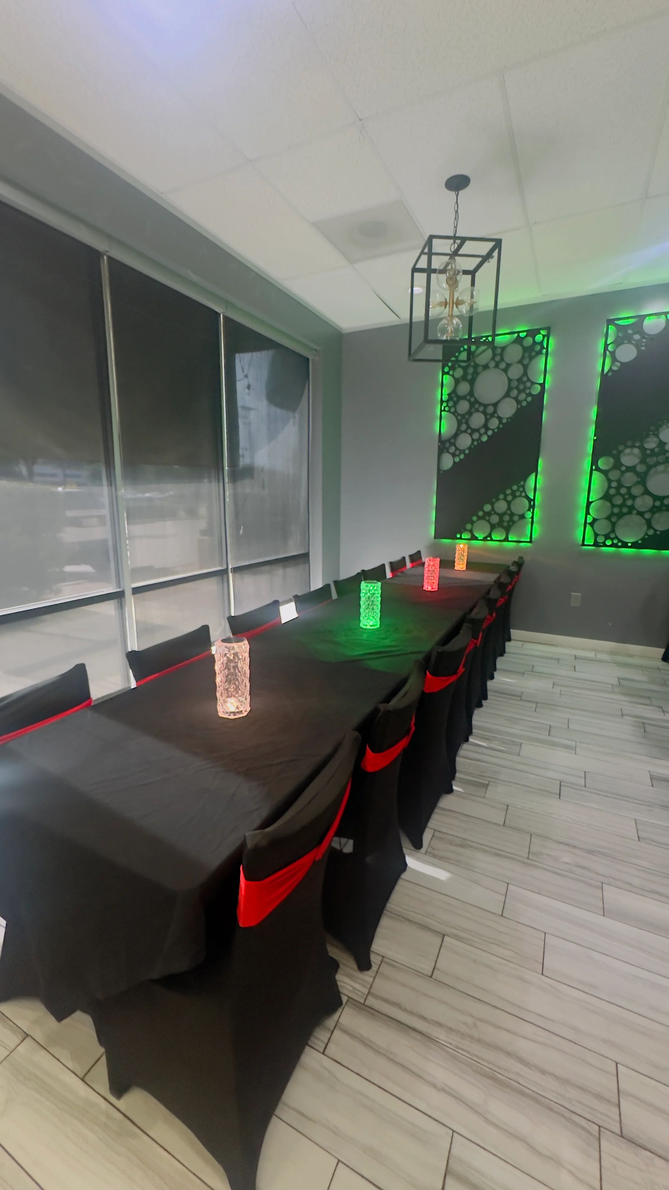 Modern restaurant dining room with black tables, red accents, and green lighting