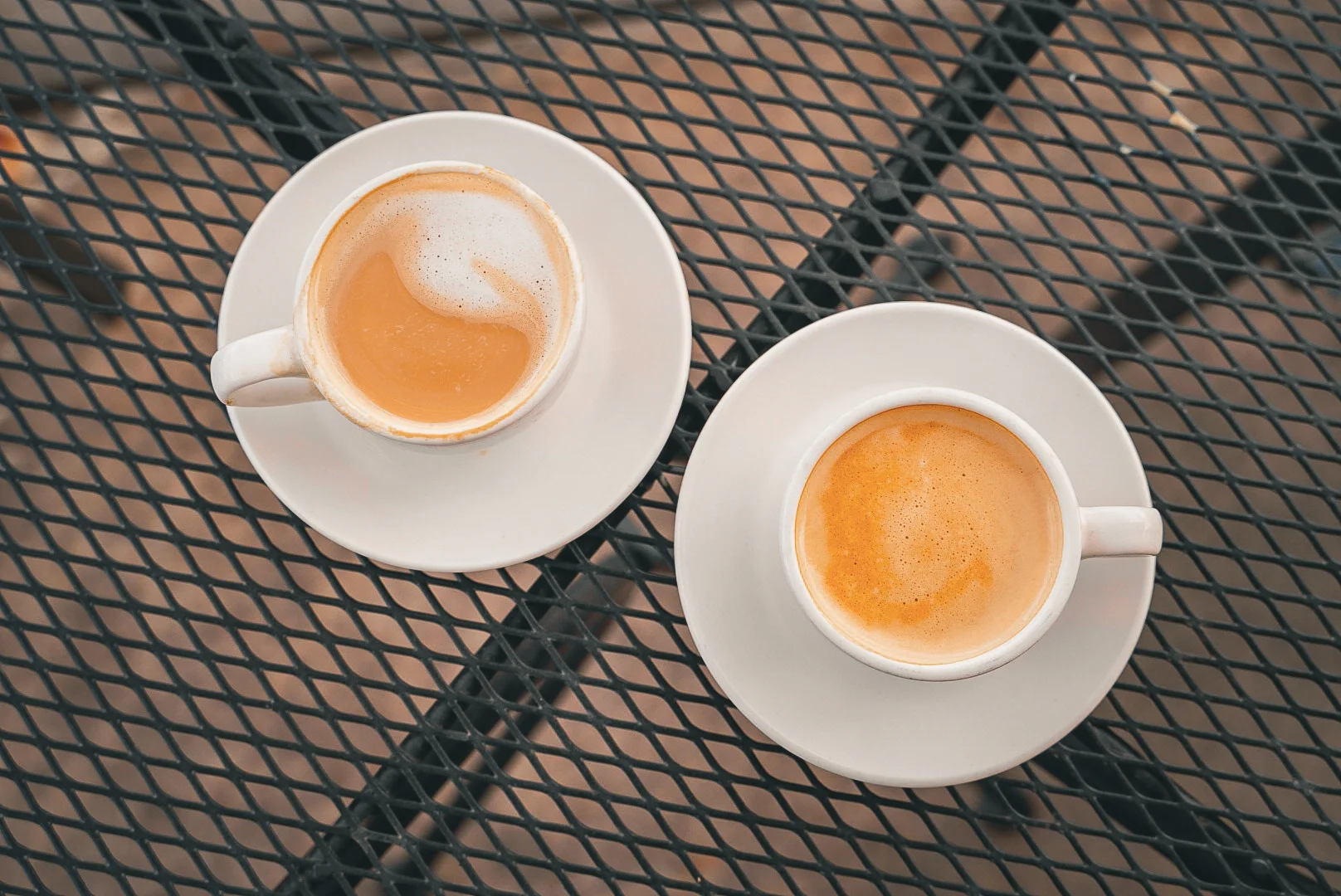 Two cups of coffee on a metal table