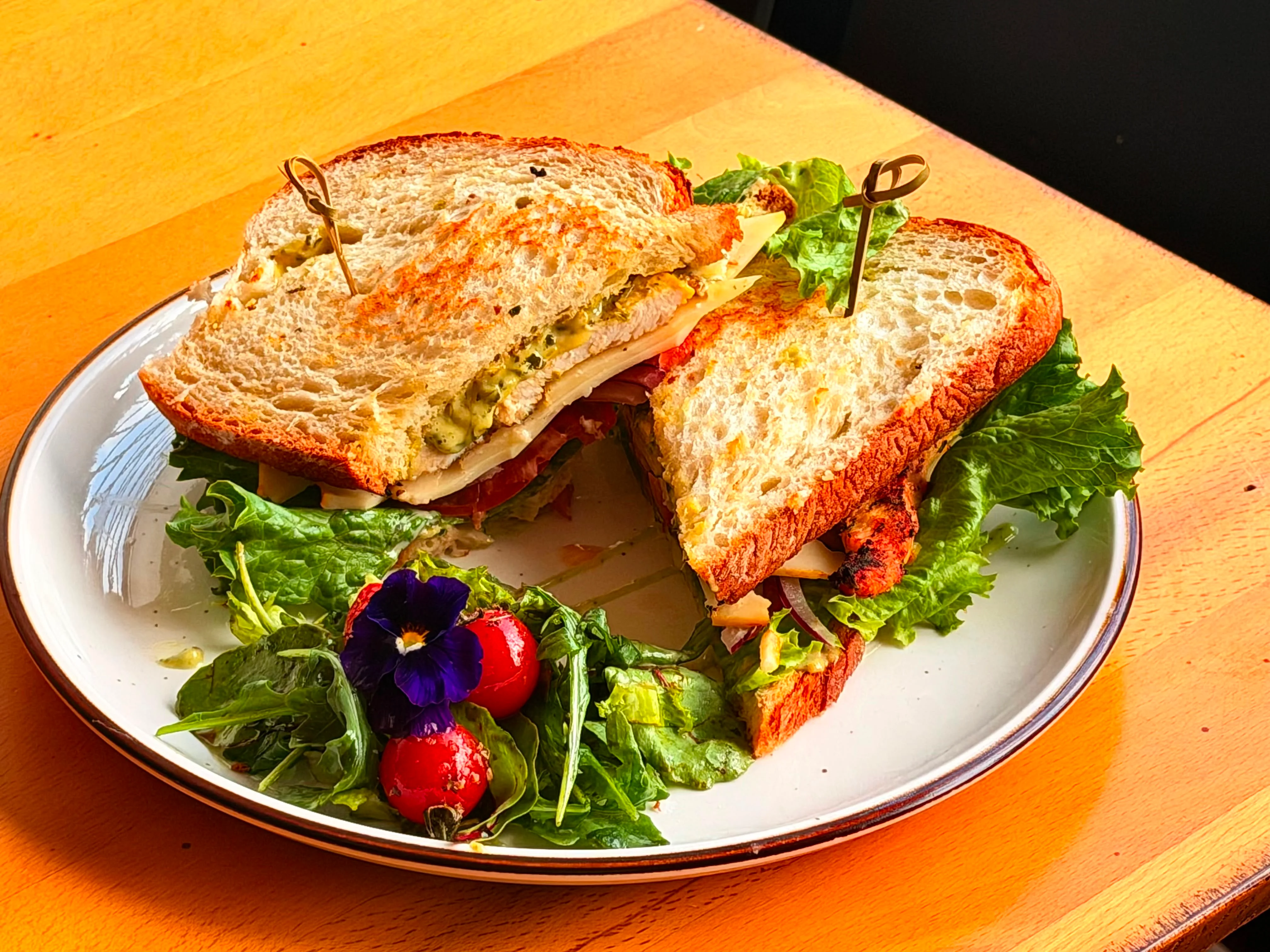 Toasted bread topped with avocado, scrambled eggs, smoked salmon, and garnished with fresh herbs and cherry tomatoes.