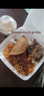 A takeout container filled with a variety of food including rice, beans, a meat-filled pastry, and shredded meat on the side.