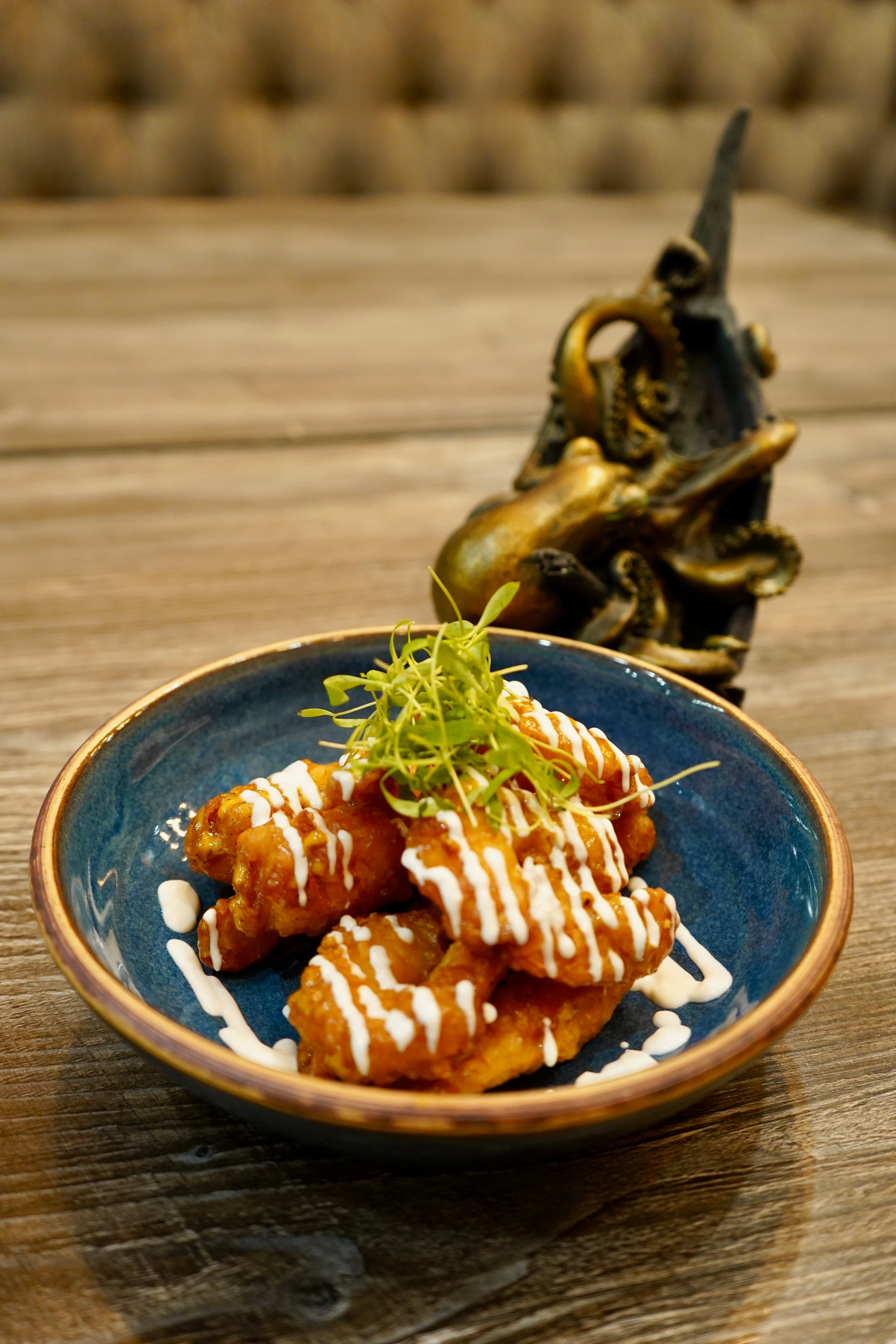 Plated fried appetizer with creamy drizzle and microgreens