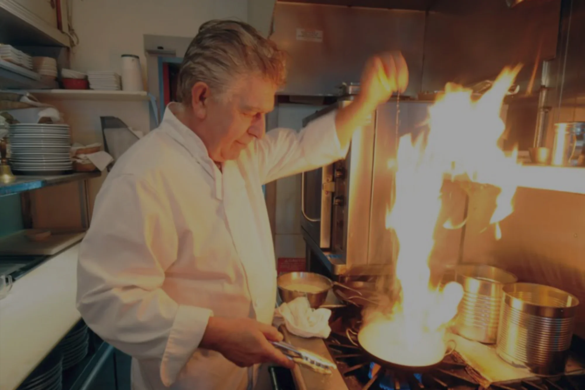 Chef flambéing a dish in a bustling kitchen