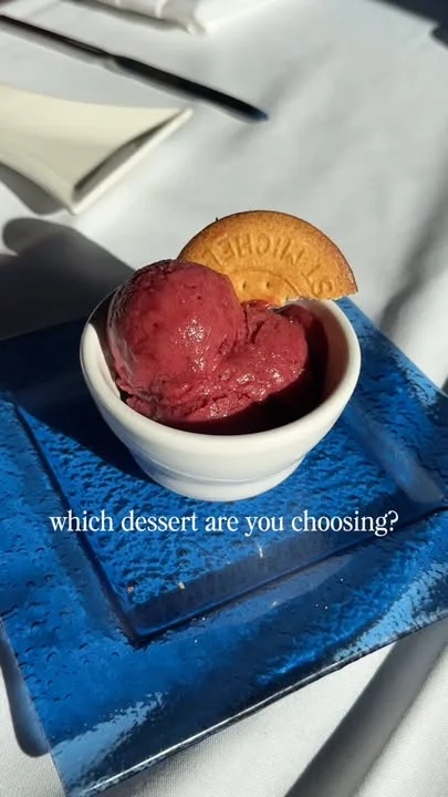 A serving of berry sorbet topped with a cookie, presented in a small dish on a blue plate.