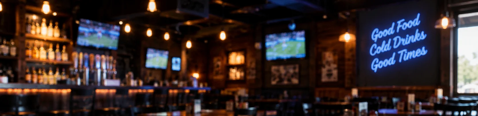 Warm sports bar interior with wooden tables, pendant lights, and televisions