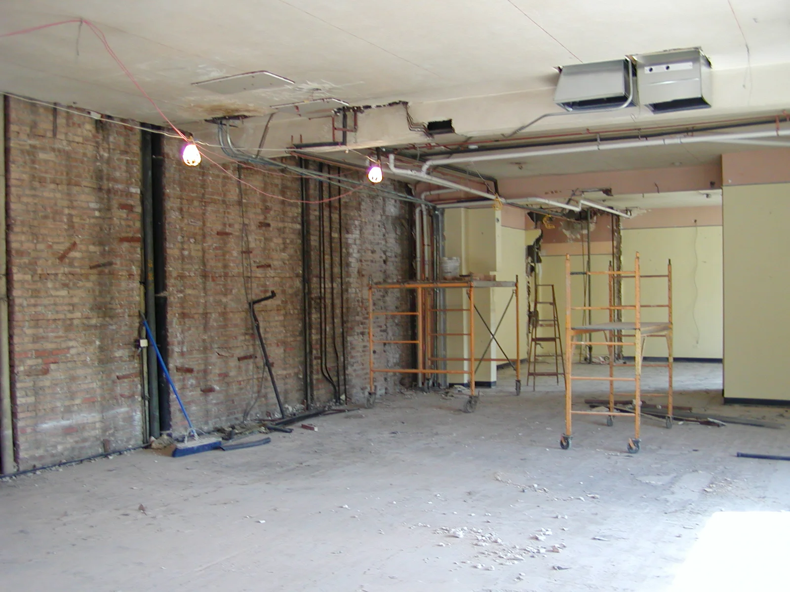 Empty restaurant space undergoing renovation with exposed brick and scaffolding