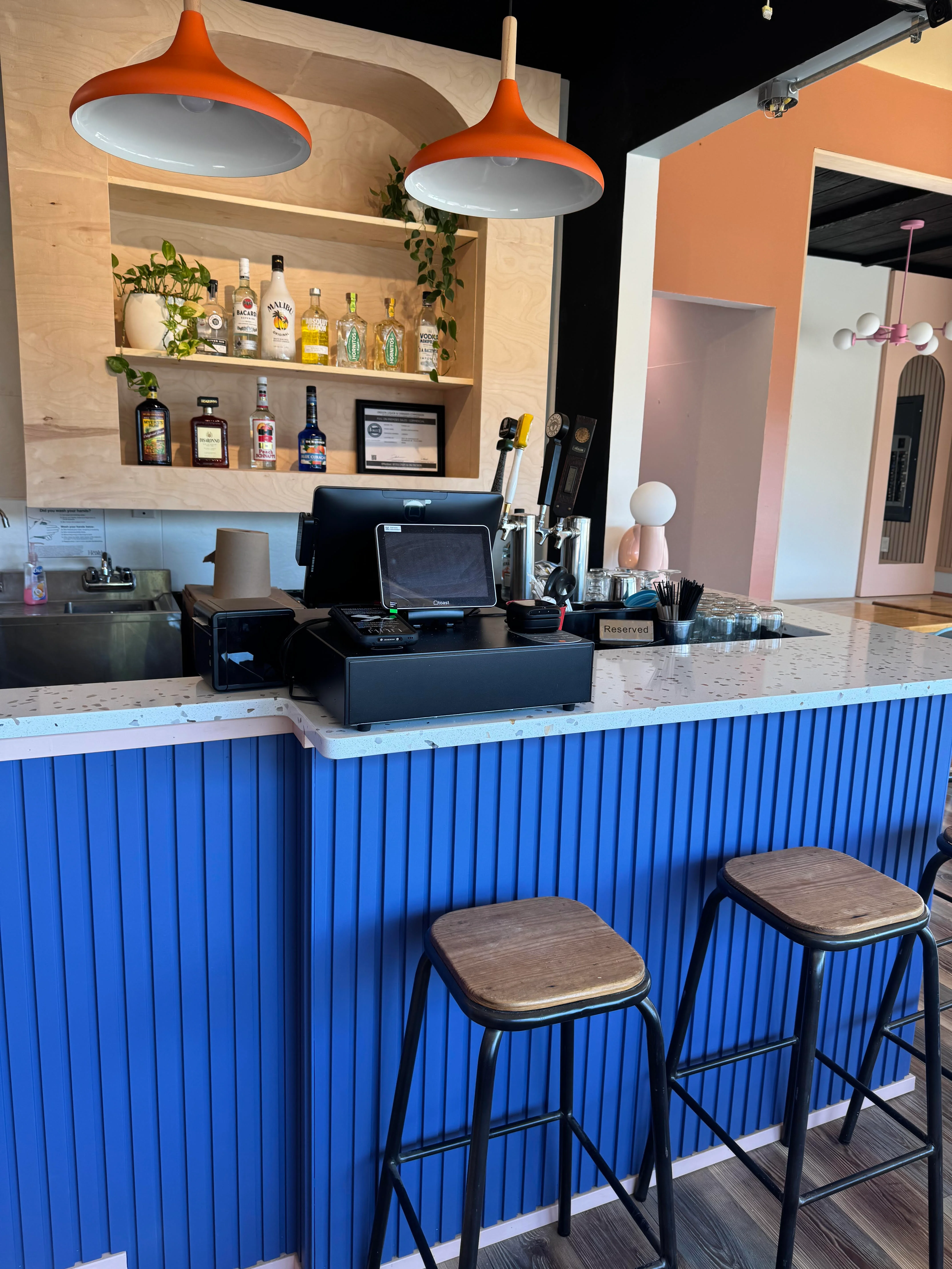 Modern bar counter with colorful pendant lights and spirits display