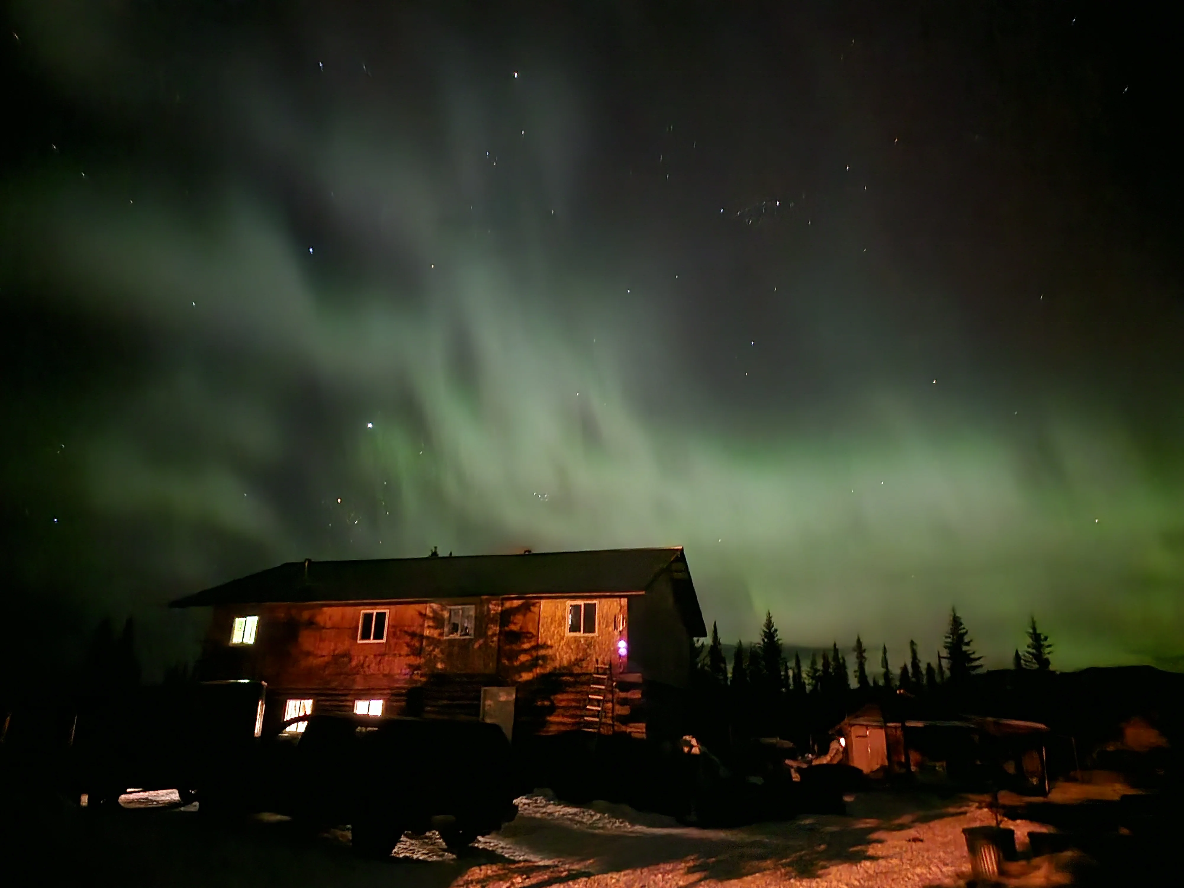 Northern Lights illuminating a rustic cabin in the wilderness