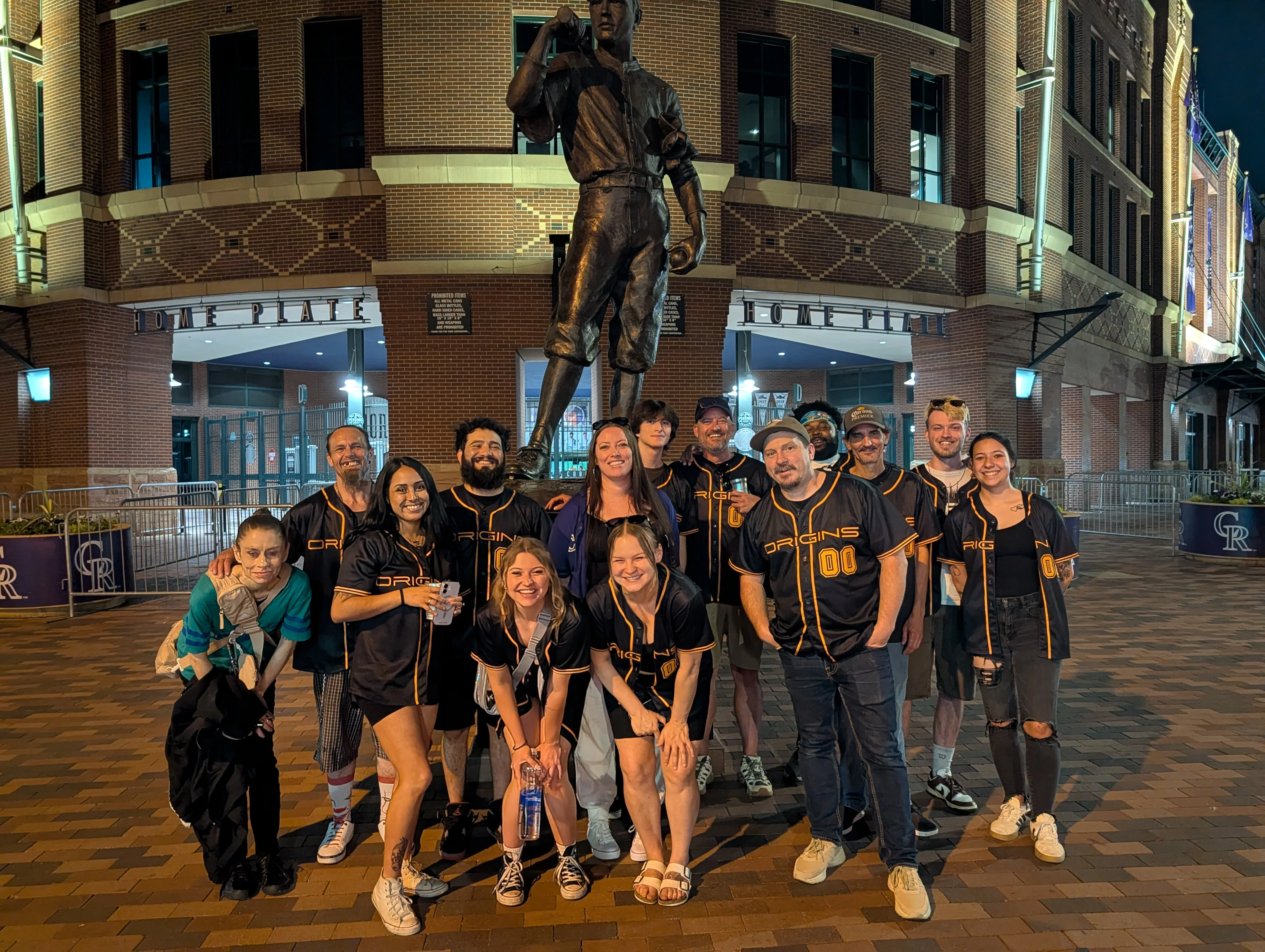 Group of friends posing at a baseball stadium statue