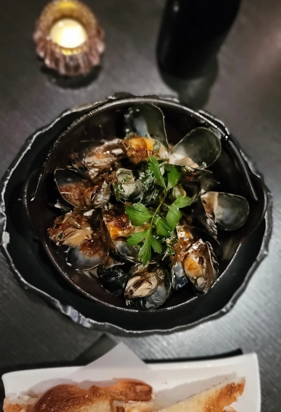 Mussels in garlic sauce served in a black bowl