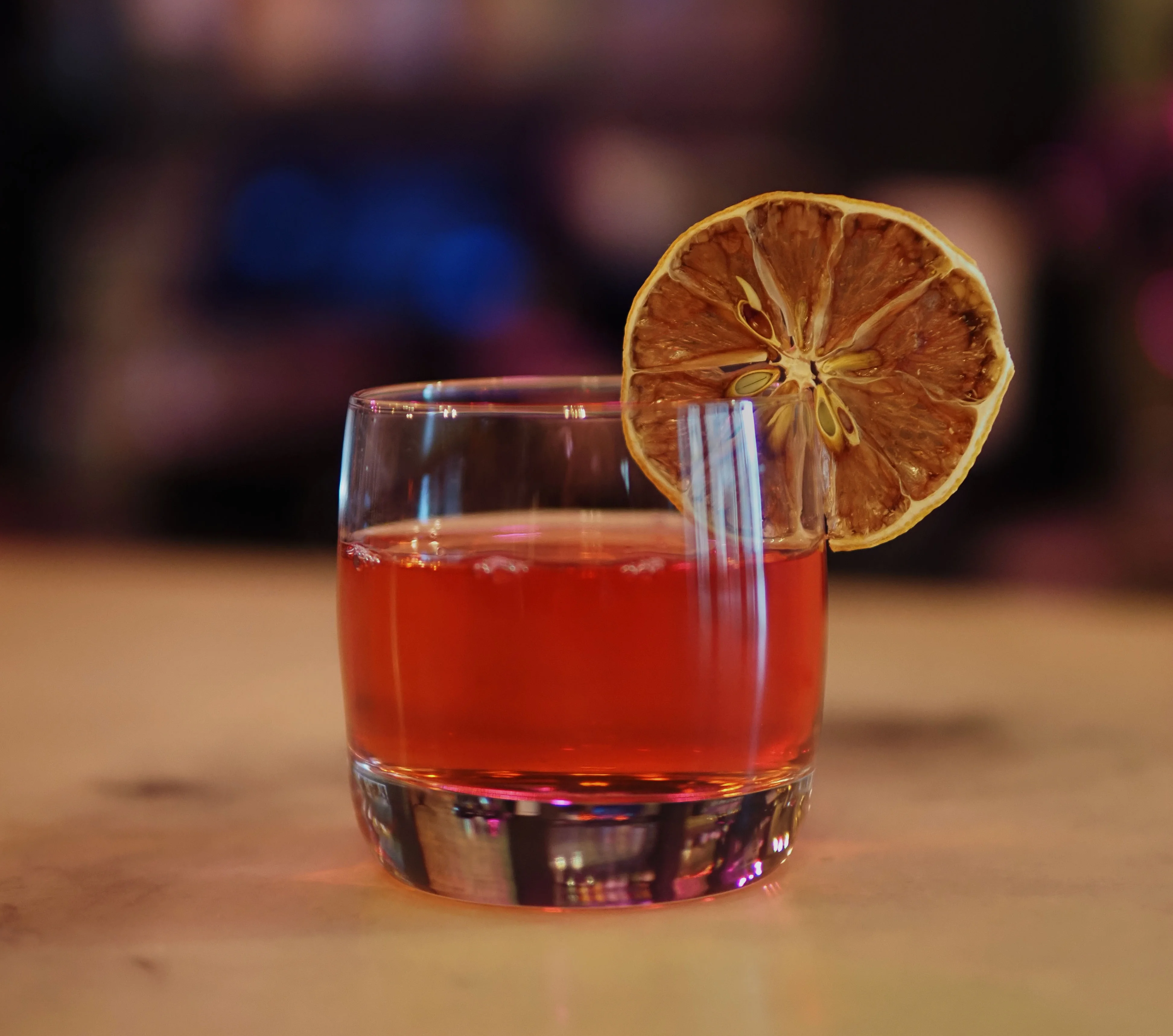 Craft cocktail with dried lemon garnish on a bar counter